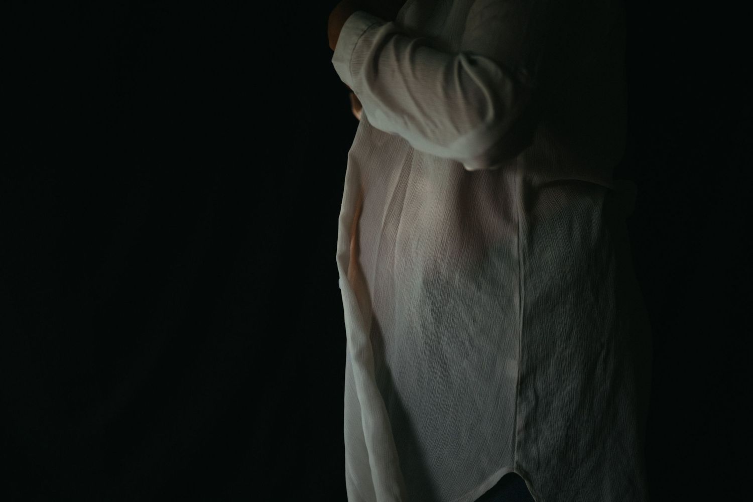 Minimalist maternity silhouette against dark background in white fabric.