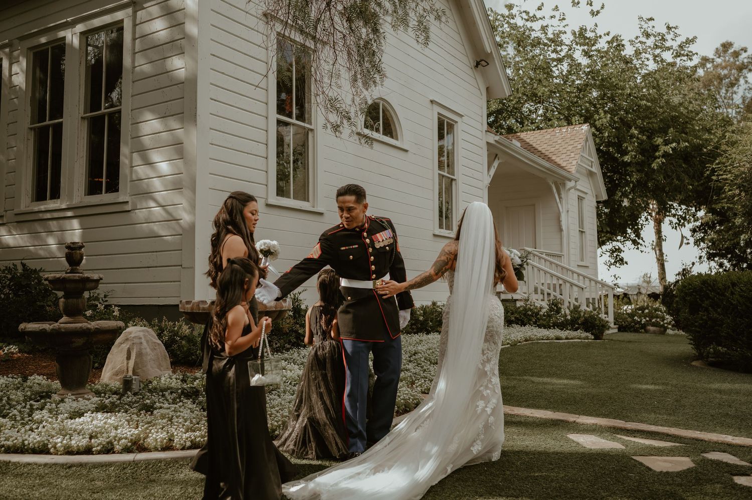 A charming white wedding venue with elegant landscaping provides a classic backdrop for the ceremony.