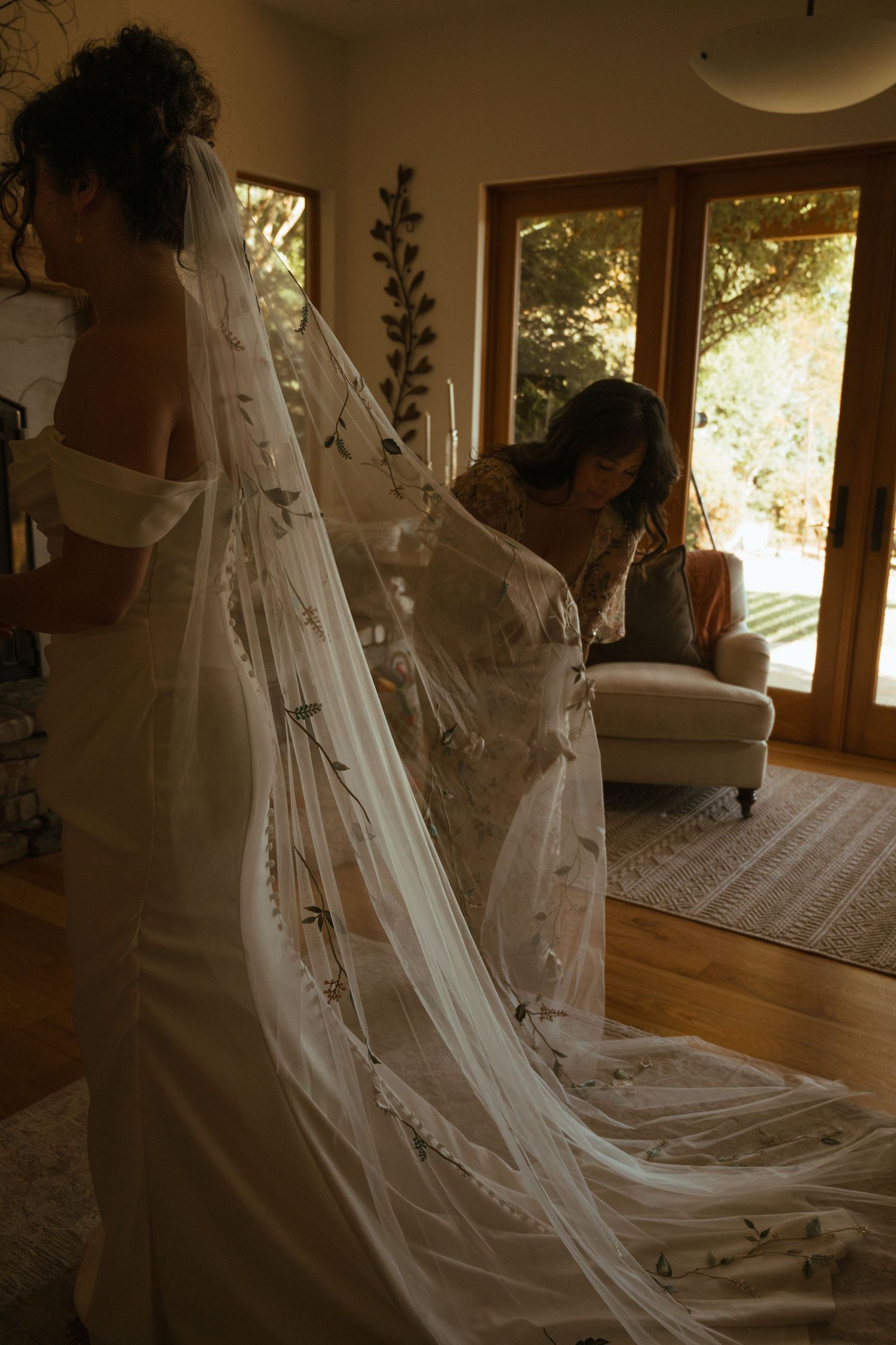 Wedding dress and veil details captured in warm natural window light.