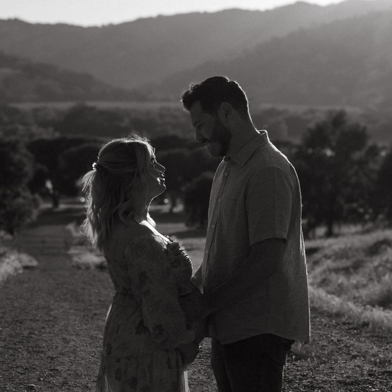 Black and white portrait of couple sharing an intimate moment on a hilltop.