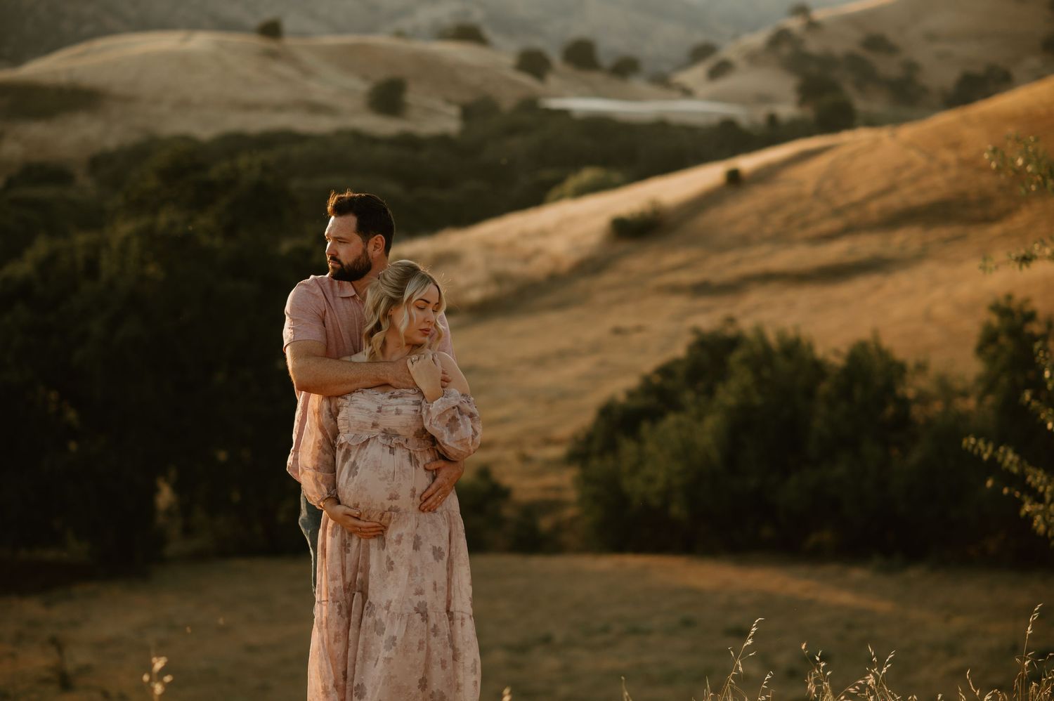 Loving couple embraces on rolling hills during golden hour photography session.