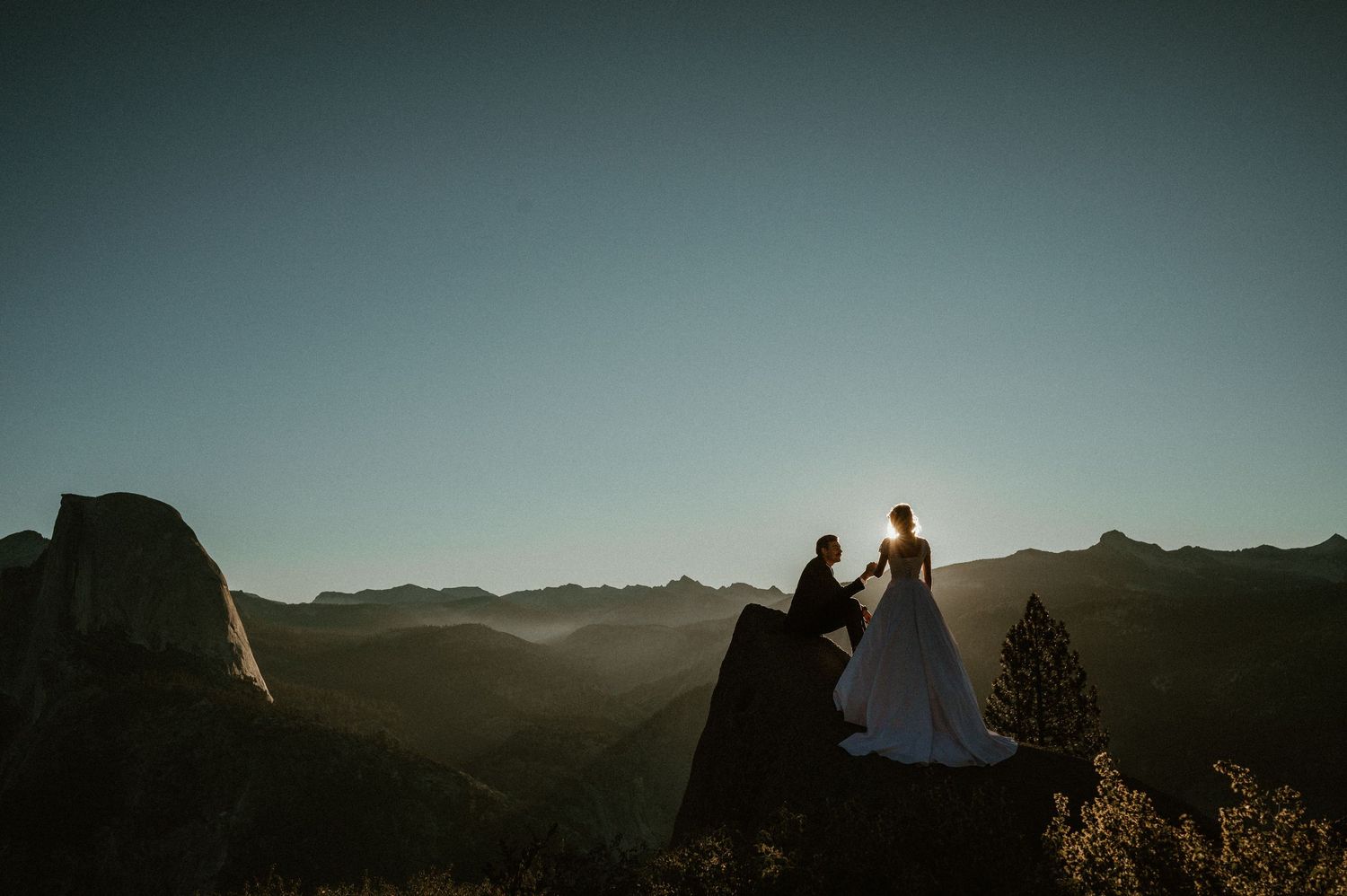 Dramatic mountain landscape at dusk with figures in silhouette.