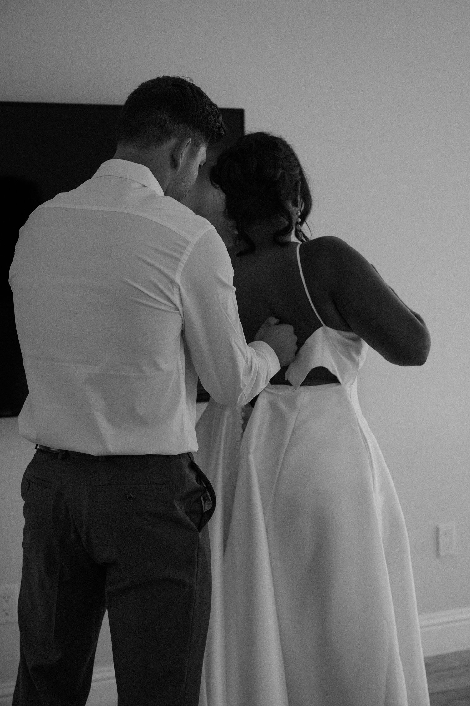 Intimate black and white moment between two people in formal attire.