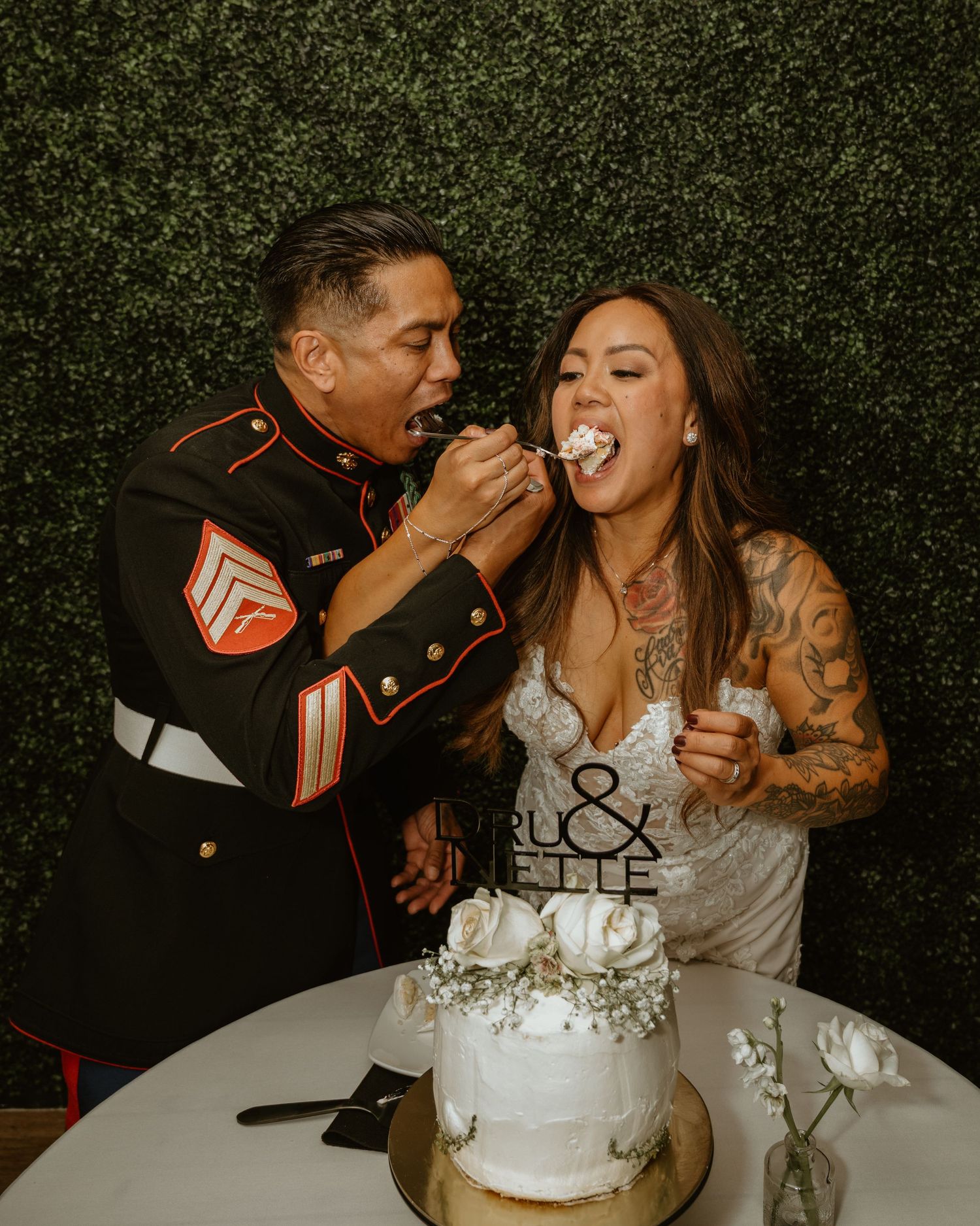Newlyweds sharing cake at their wedding reception with playful expressions.