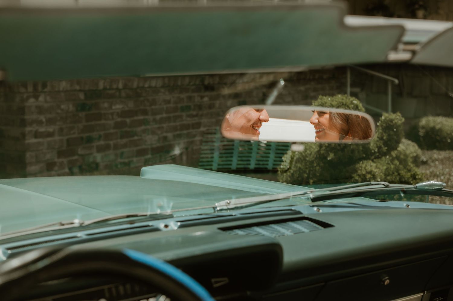 Vintage sports car parked near stone wall with retro styling.