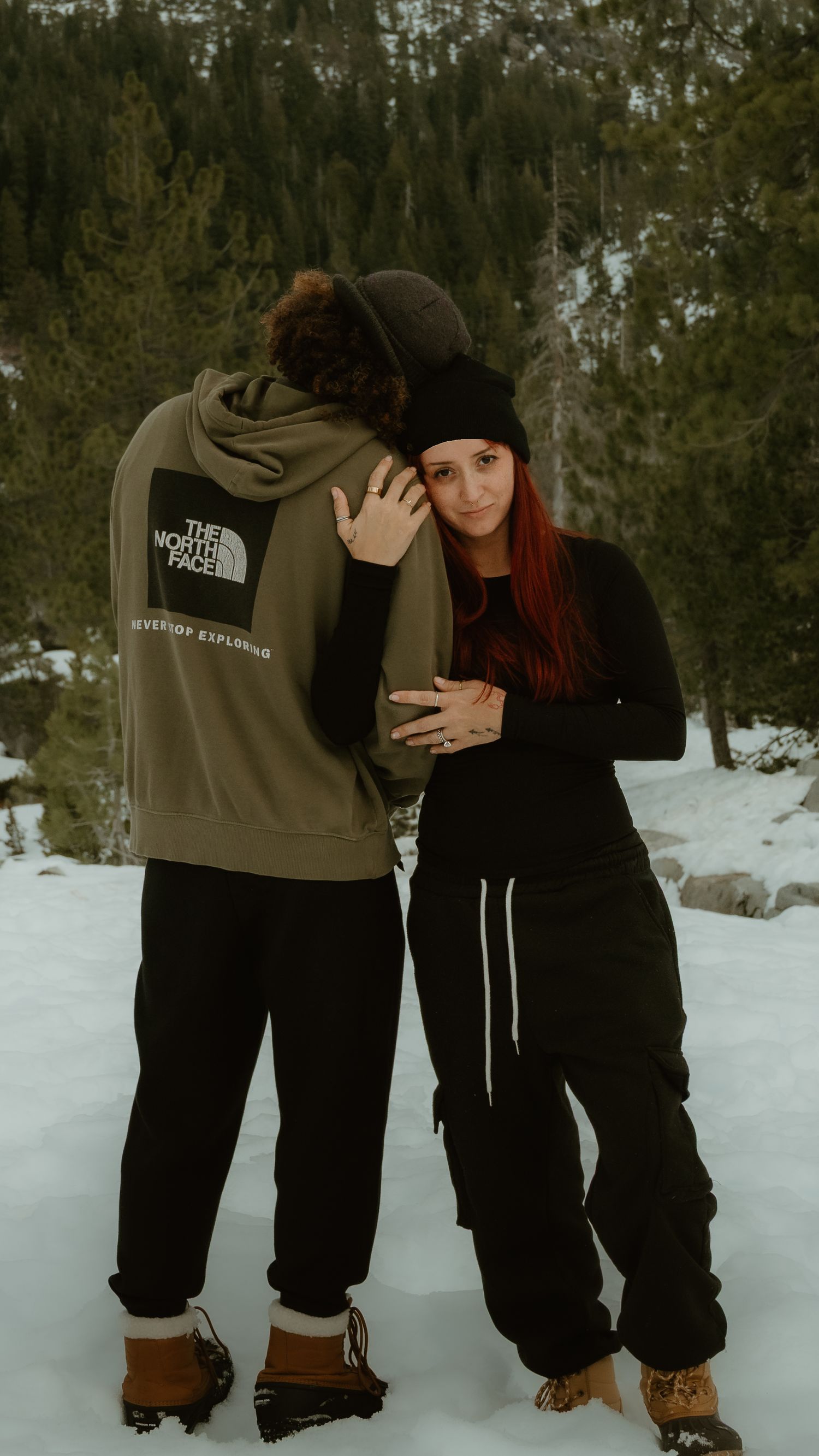 Winter outdoor photoshoot featuring casual outfits and snow-covered forest scenery.