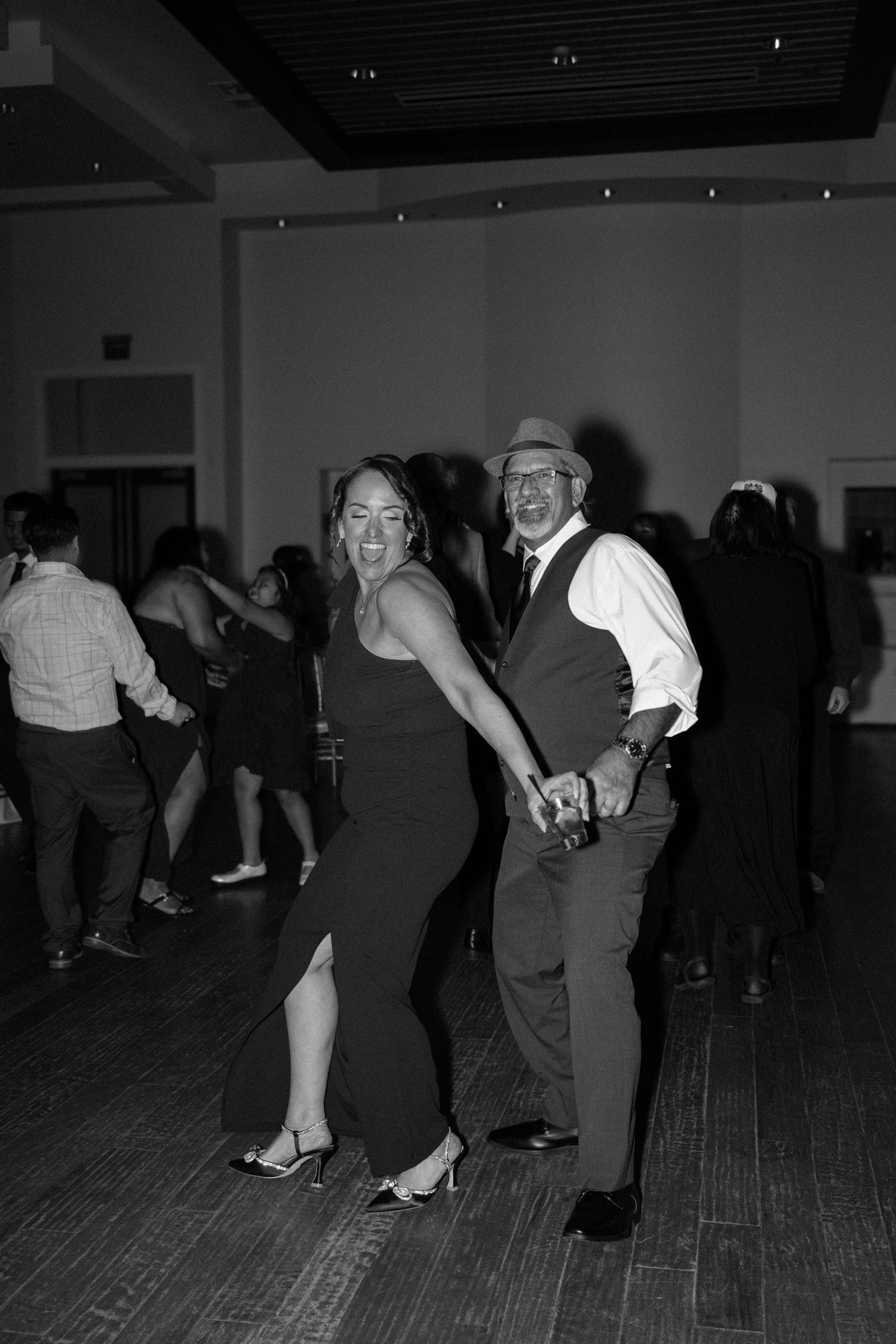 Couple dancing in vintage style on hardwood floor during evening celebration.