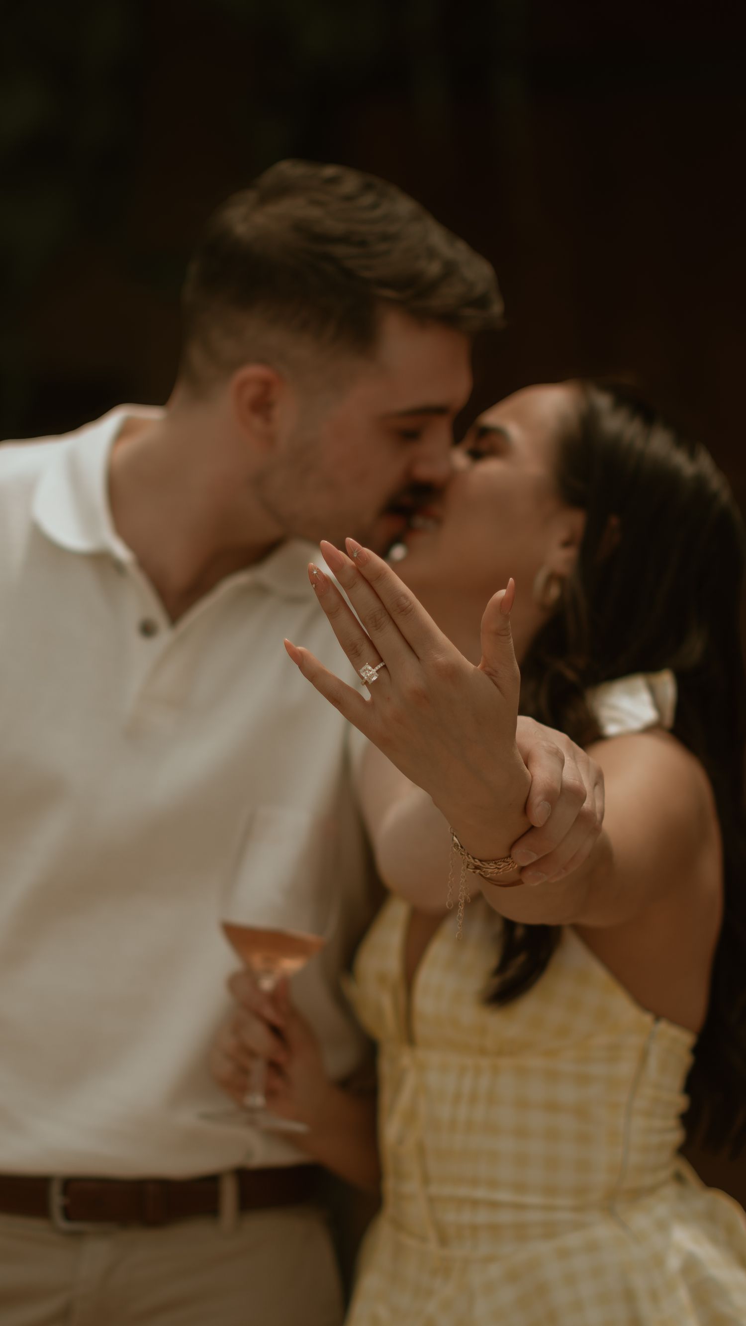 A happy couple sharing their first kiss as newly engaged, with the ring prominently displayed.
