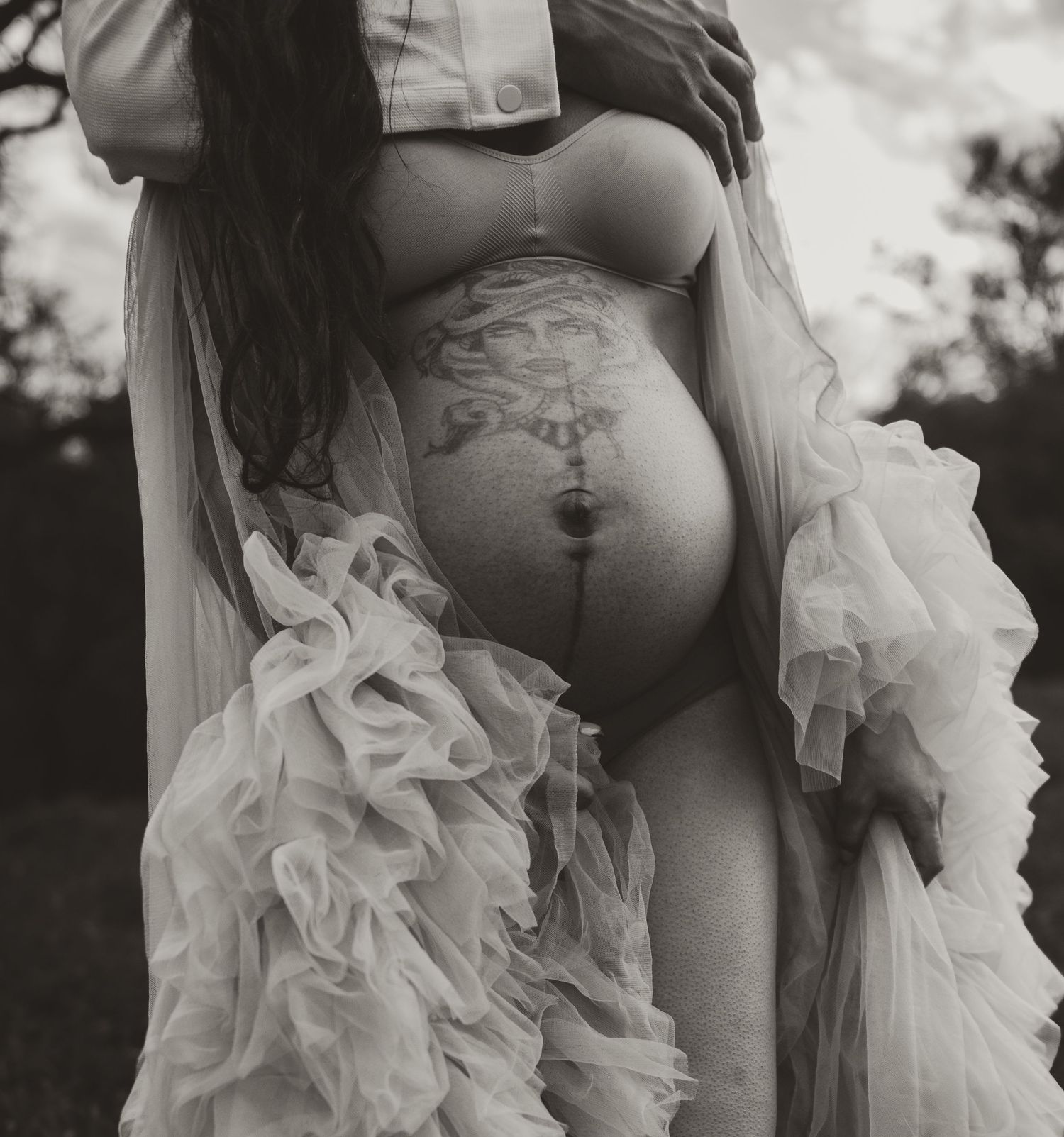 Artistic black and white maternity photo featuring delicate tulle fabric.