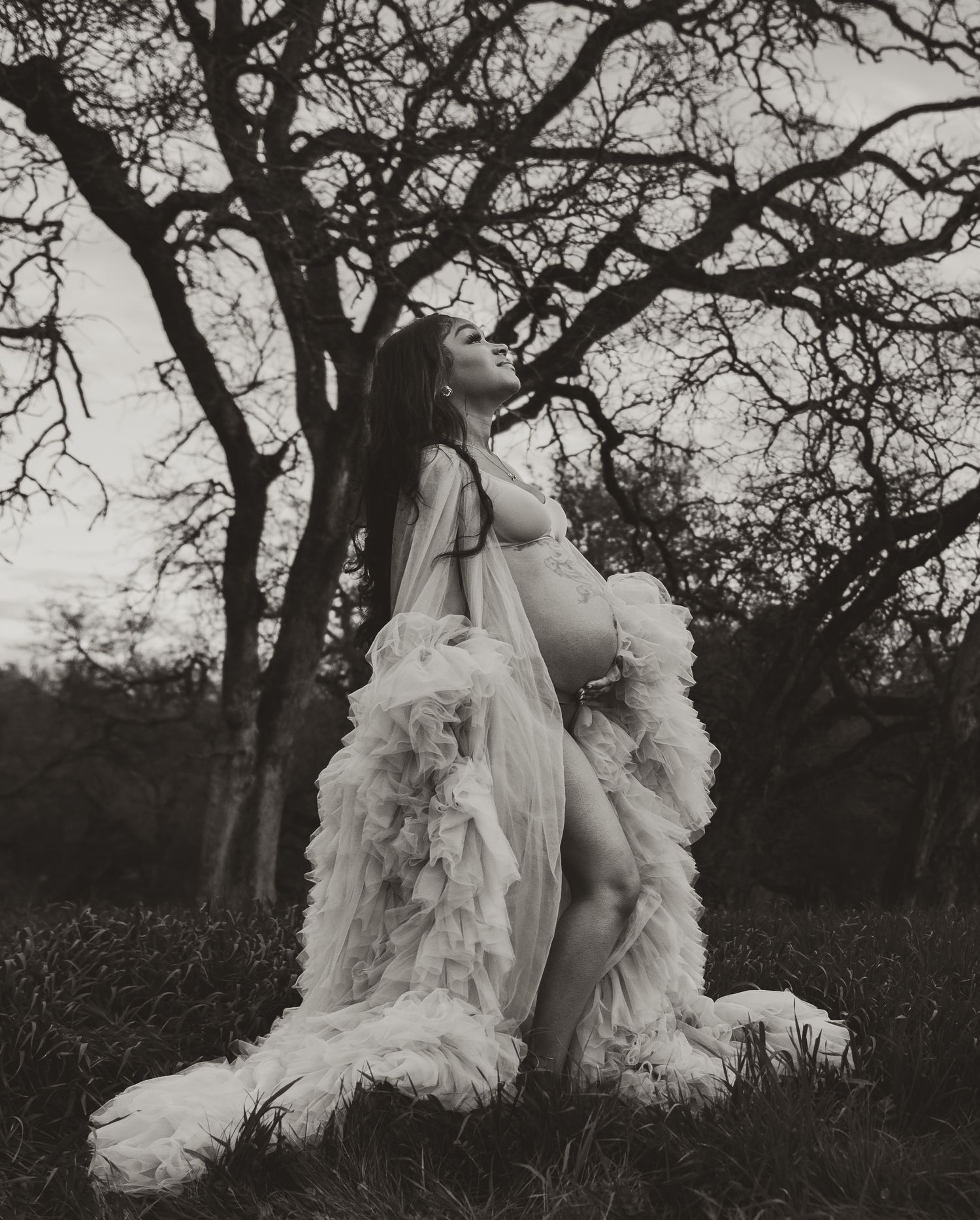 Dramatic black and white portrait under a tree with flowing tulle dress.
