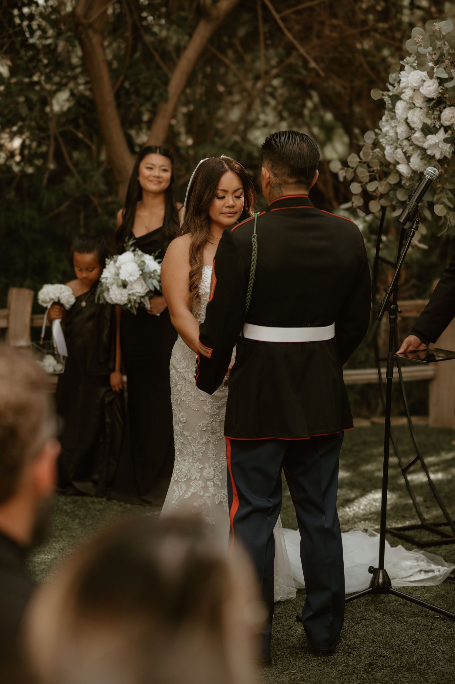 Outdoor wedding ceremony under flowering trees with military service member.