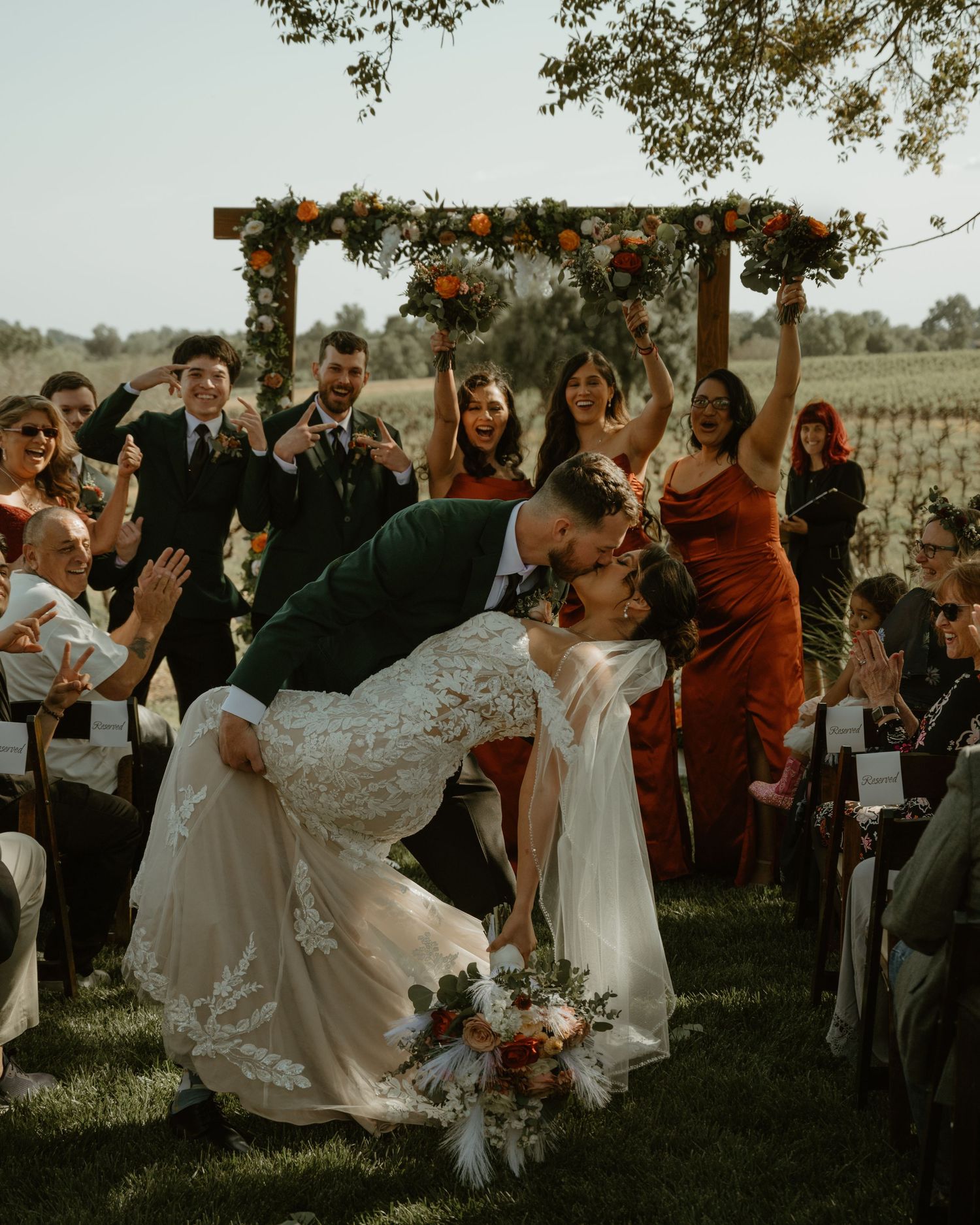 Wedding celebration with guests mingling under trees during golden hour outdoor reception.