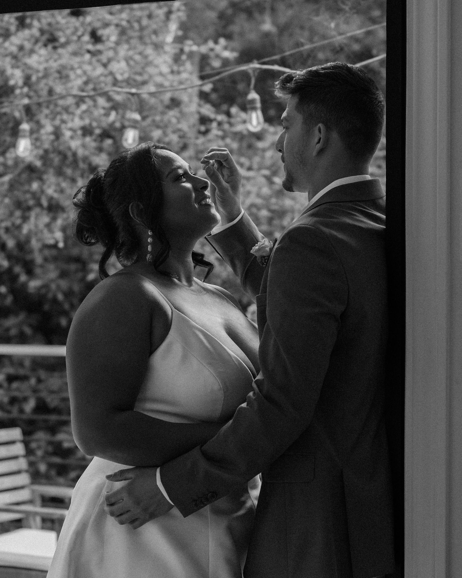 A tender romantic moment between newlyweds captured in dramatic window light.
