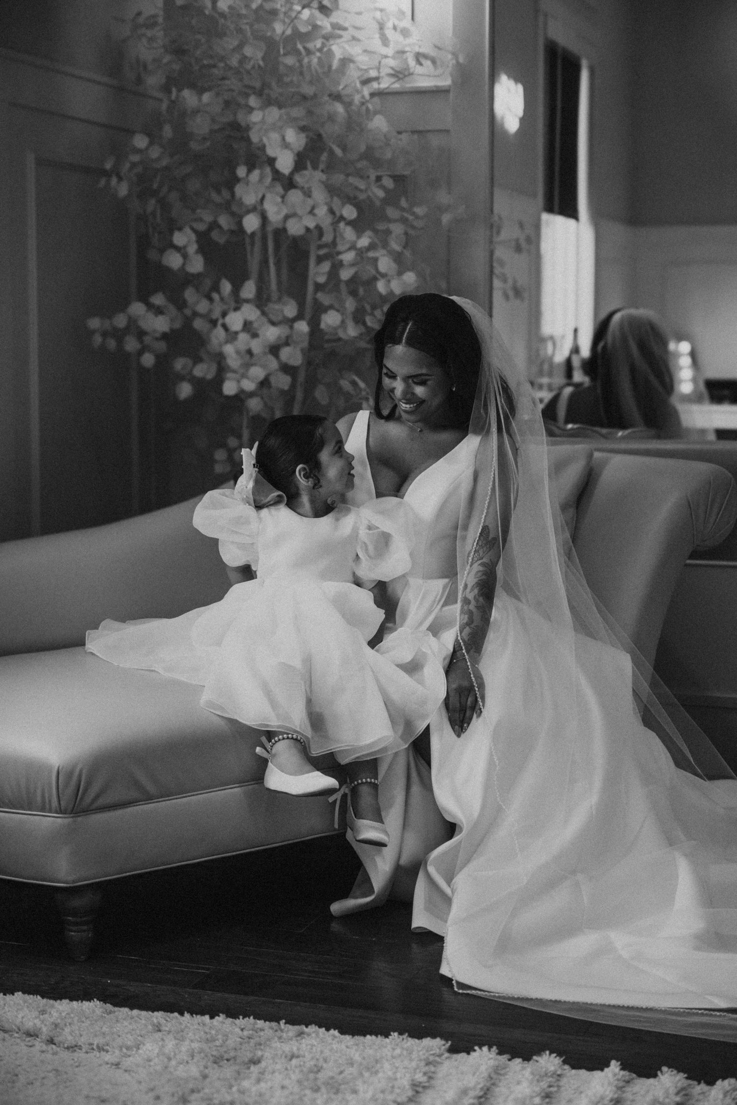A tender moment shared in formal white attire on an elegant couch.