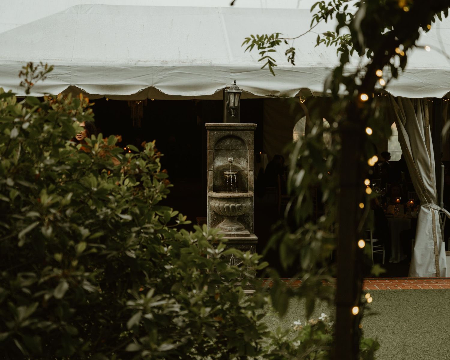 Outdoor wedding reception tent decorated with string lights creating a romantic ambiance.