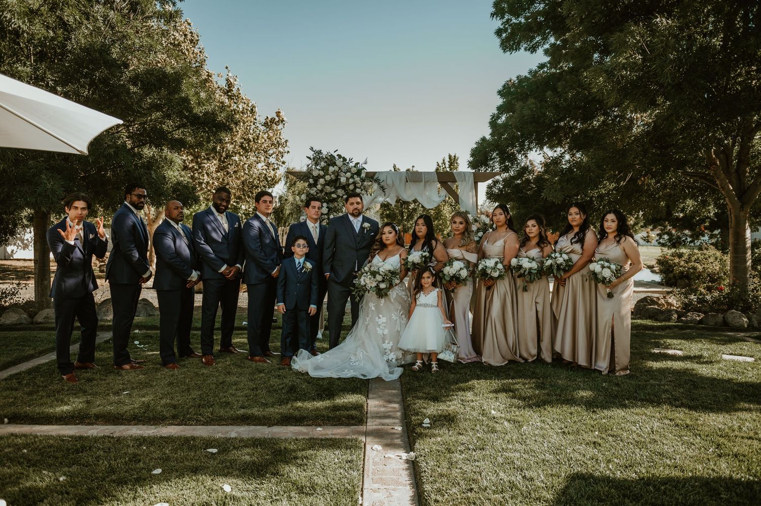 Outdoor wedding ceremony setup with guests gathered in a garden setting.