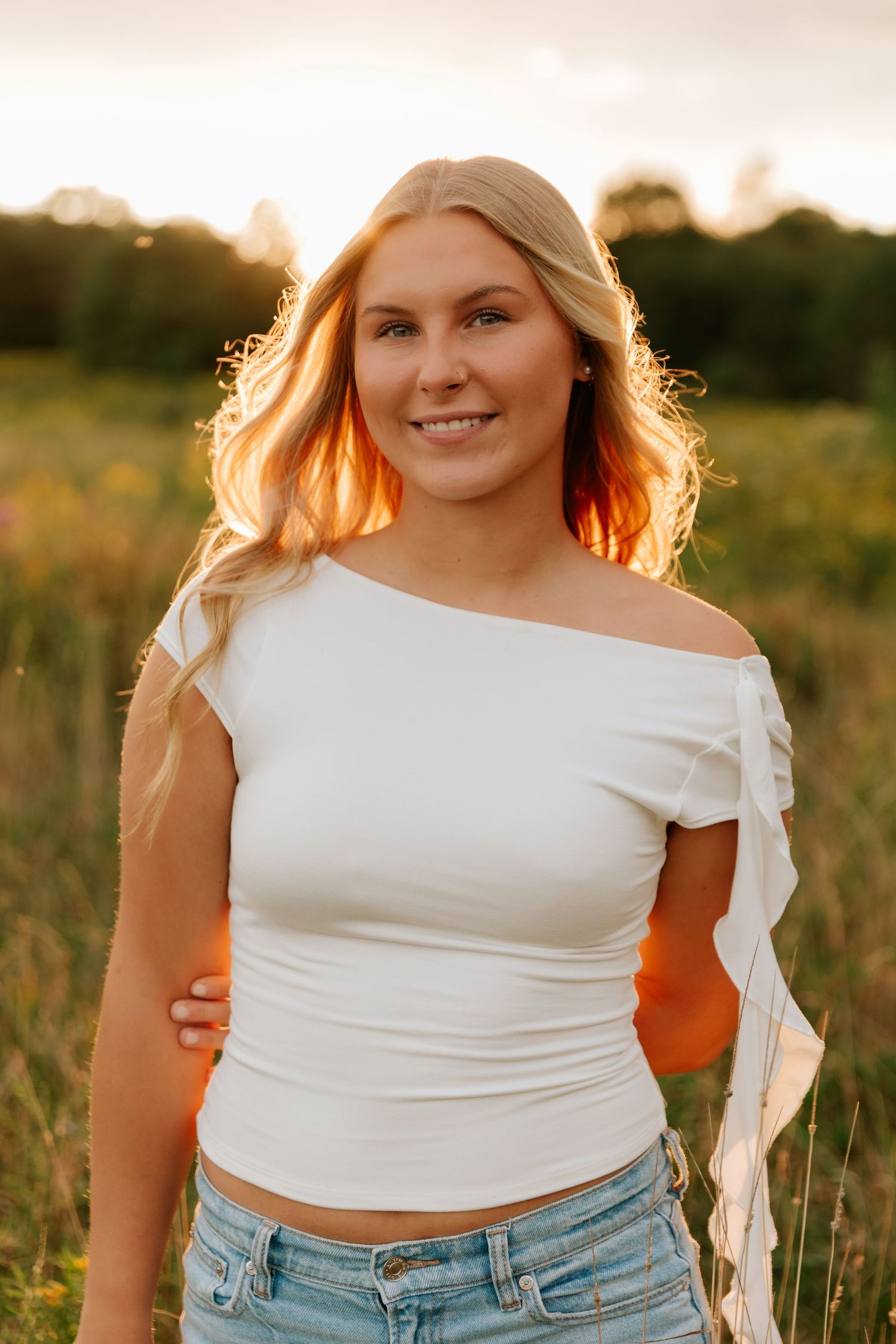 Portrait session in a sunlit field during golden hour with warm lighting effects.