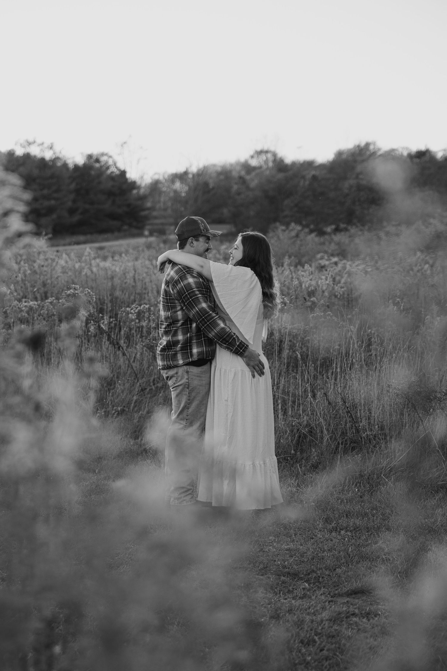 A black and white engagement photo of a couple embracing in a misty meadow in Central Pennsylvania