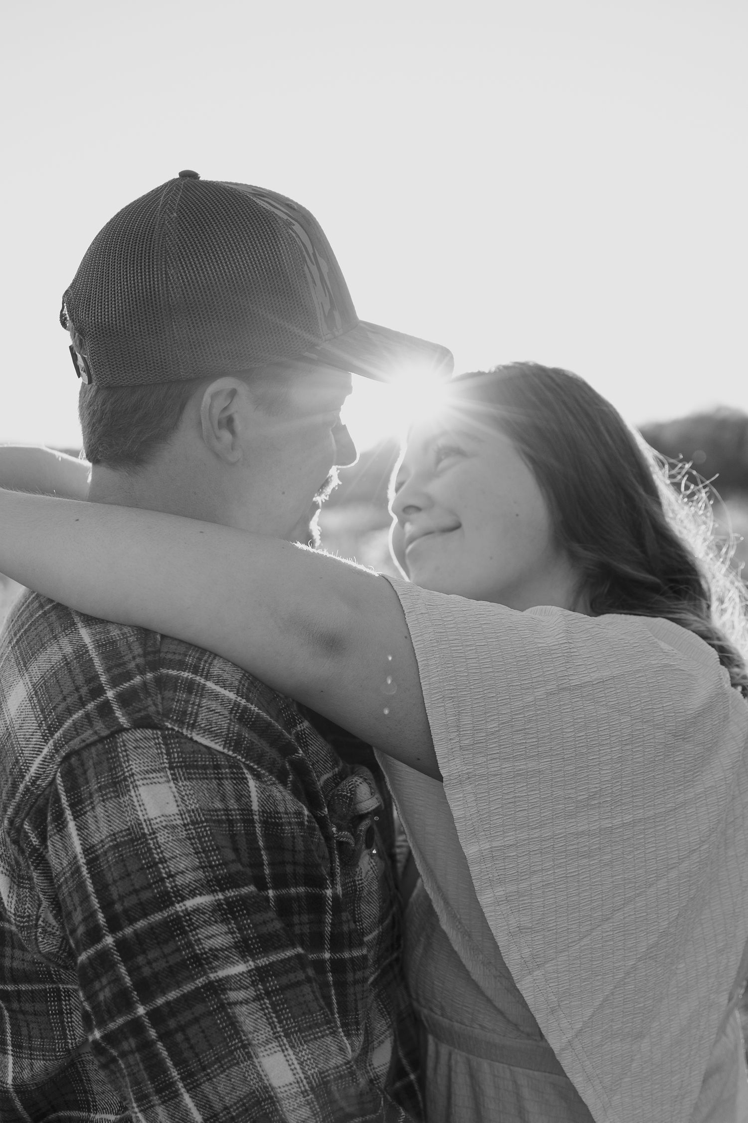 Intimate backlit silhouette of couple embracing during sunset outdoors.