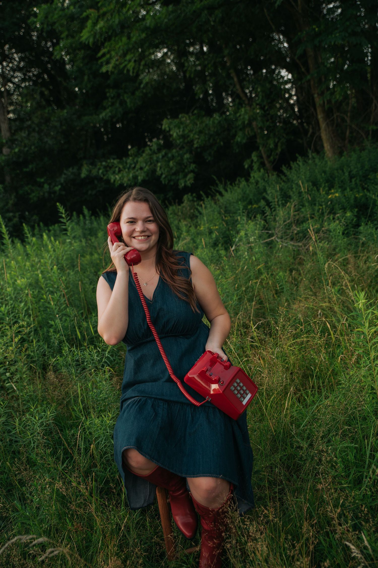 Portrait session in tall grass with vintage red telephone as a prop.