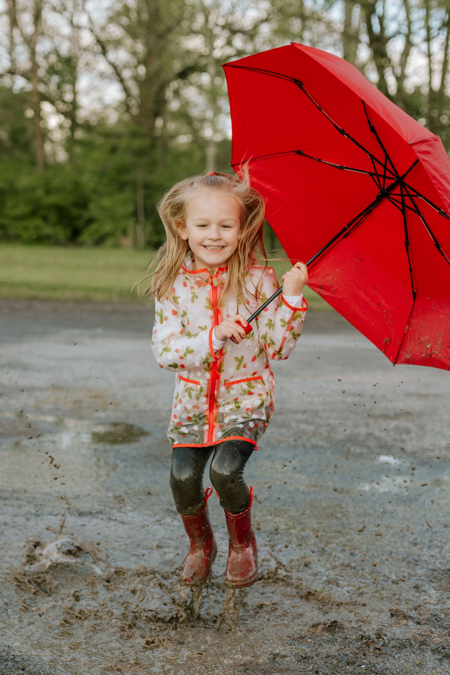 Playful outdoor photos with red umbrella and rain boots in puddles.