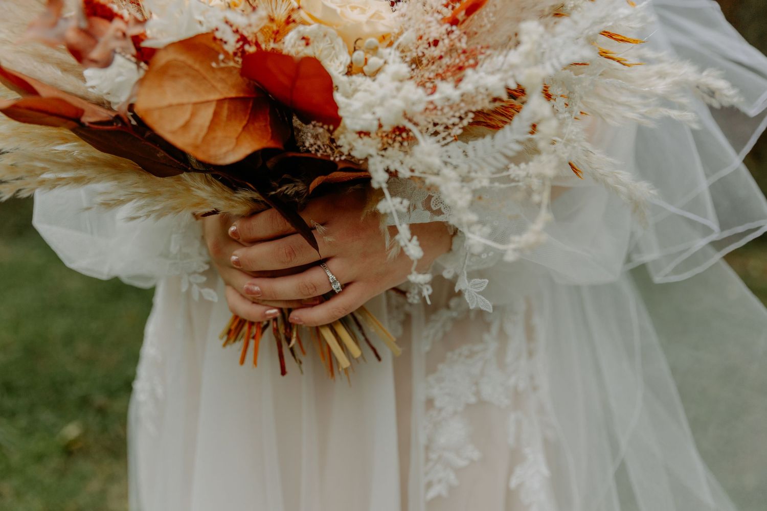 Close-up view of a bride's white lace dress with delicate beading and floral details.