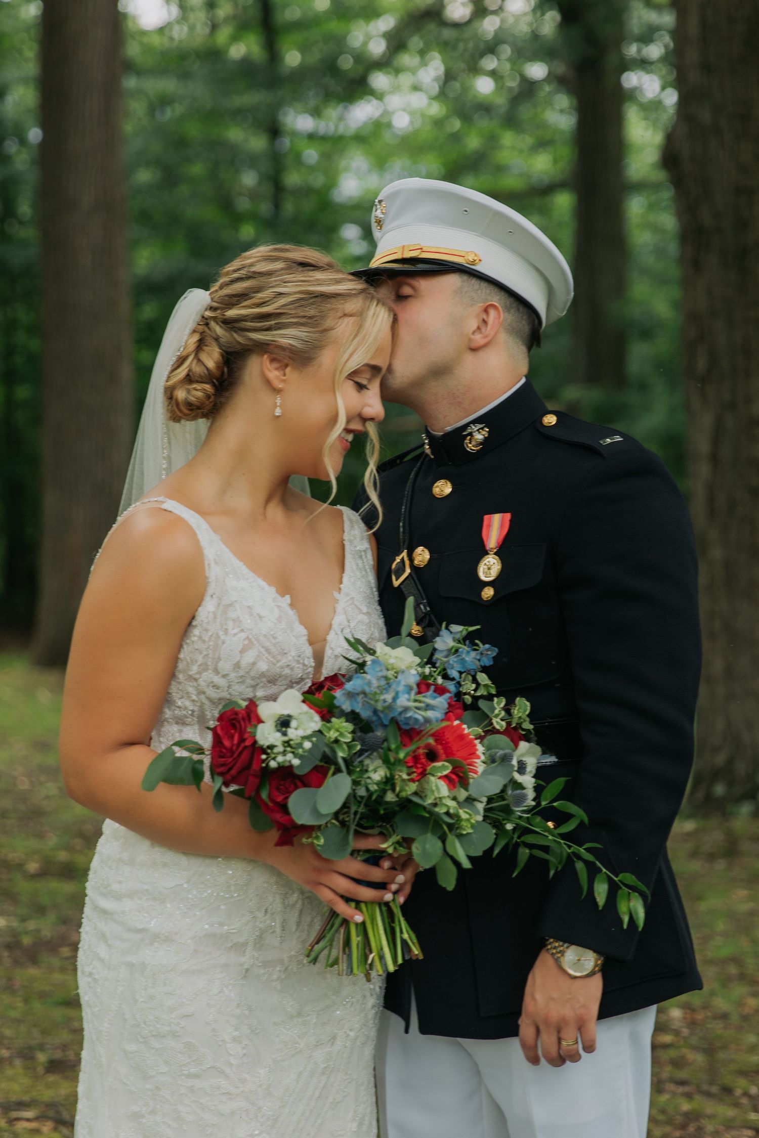 A military wedding photo featuring a formal dress uniform and colorful red and blue bouquet.