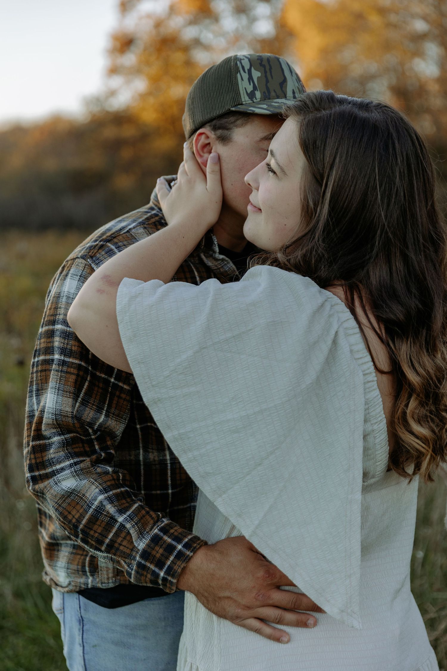 Romantic couple embracing outdoors during autumn photo session.
