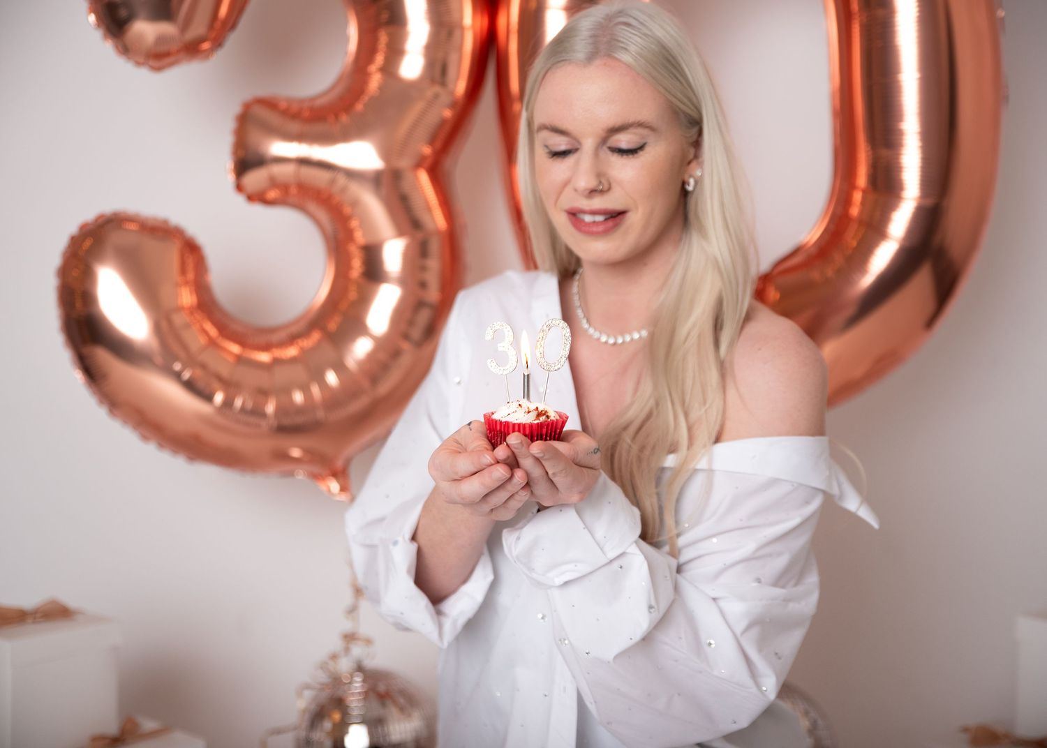 Celebratory scene with metallic number balloons and white decorative elements in soft lighting.