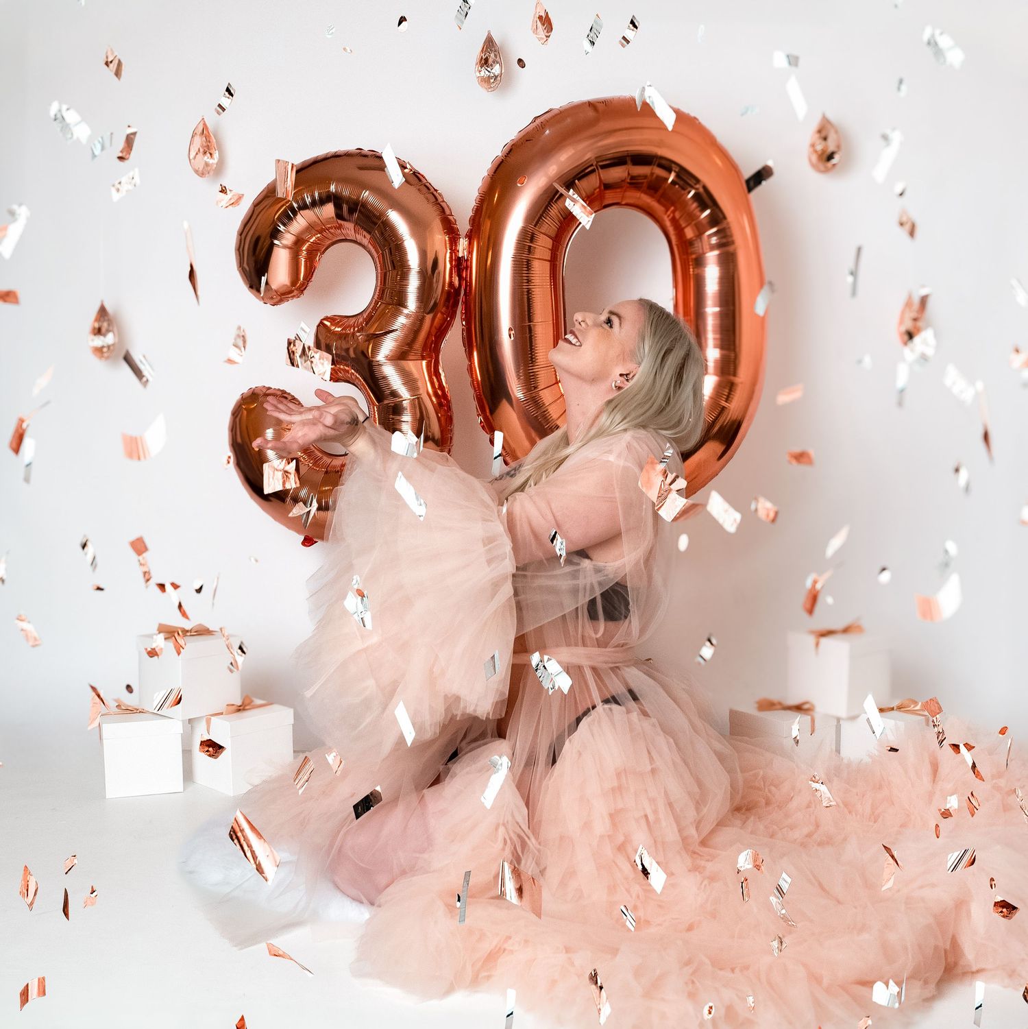Rose gold balloons and confetti create festive celebration scene against white backdrop.