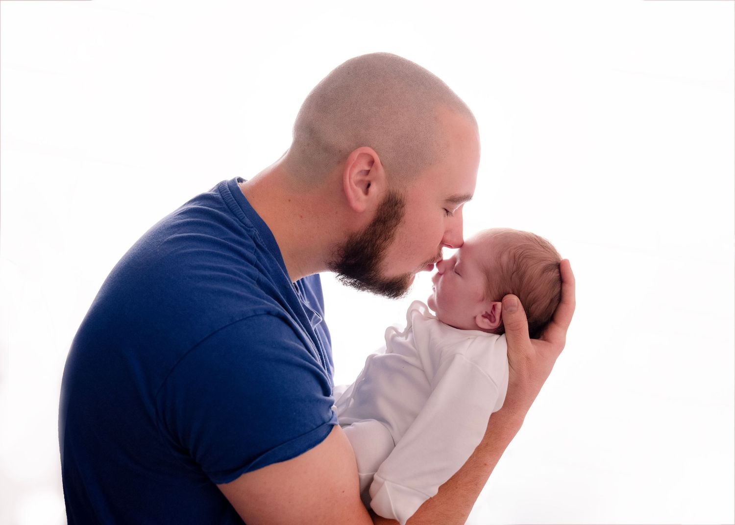 Parent in navy shirt cradling newborn baby against white background.