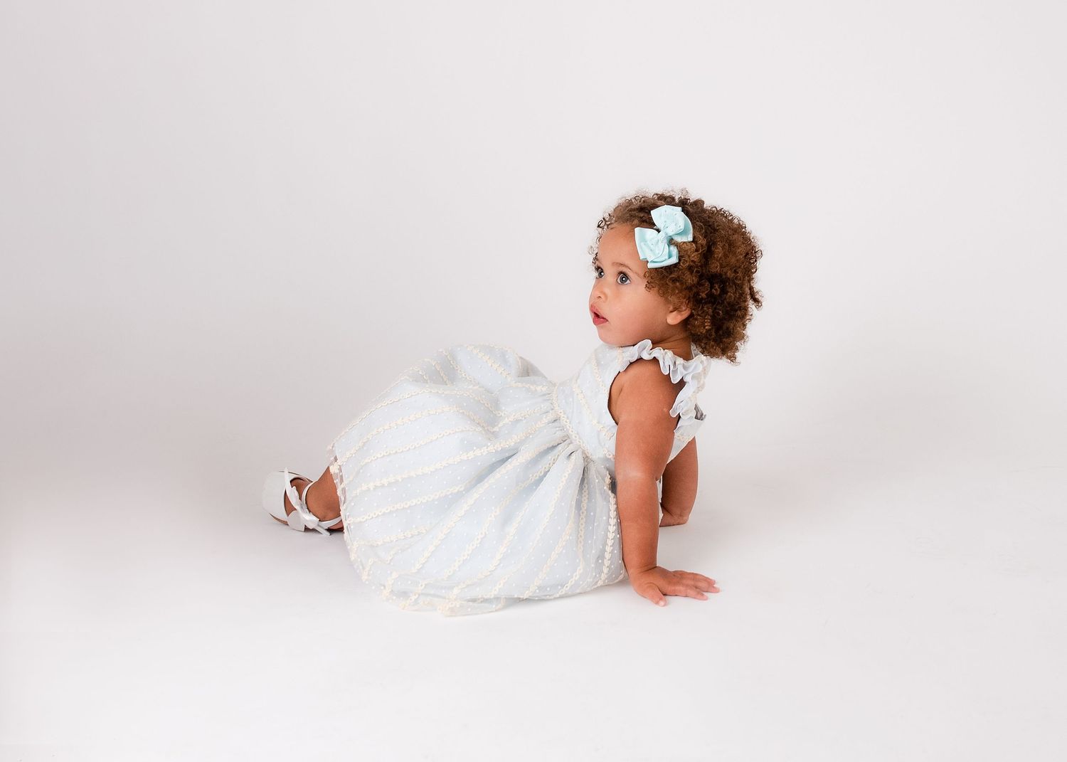 Sweet newborn portrait session with baby in white dress on clean white background.