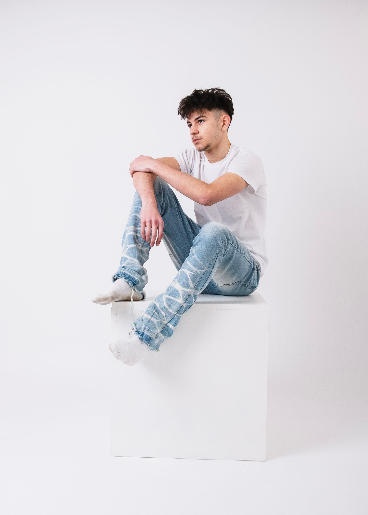 Person wearing light colored clothing poses on white backdrop.