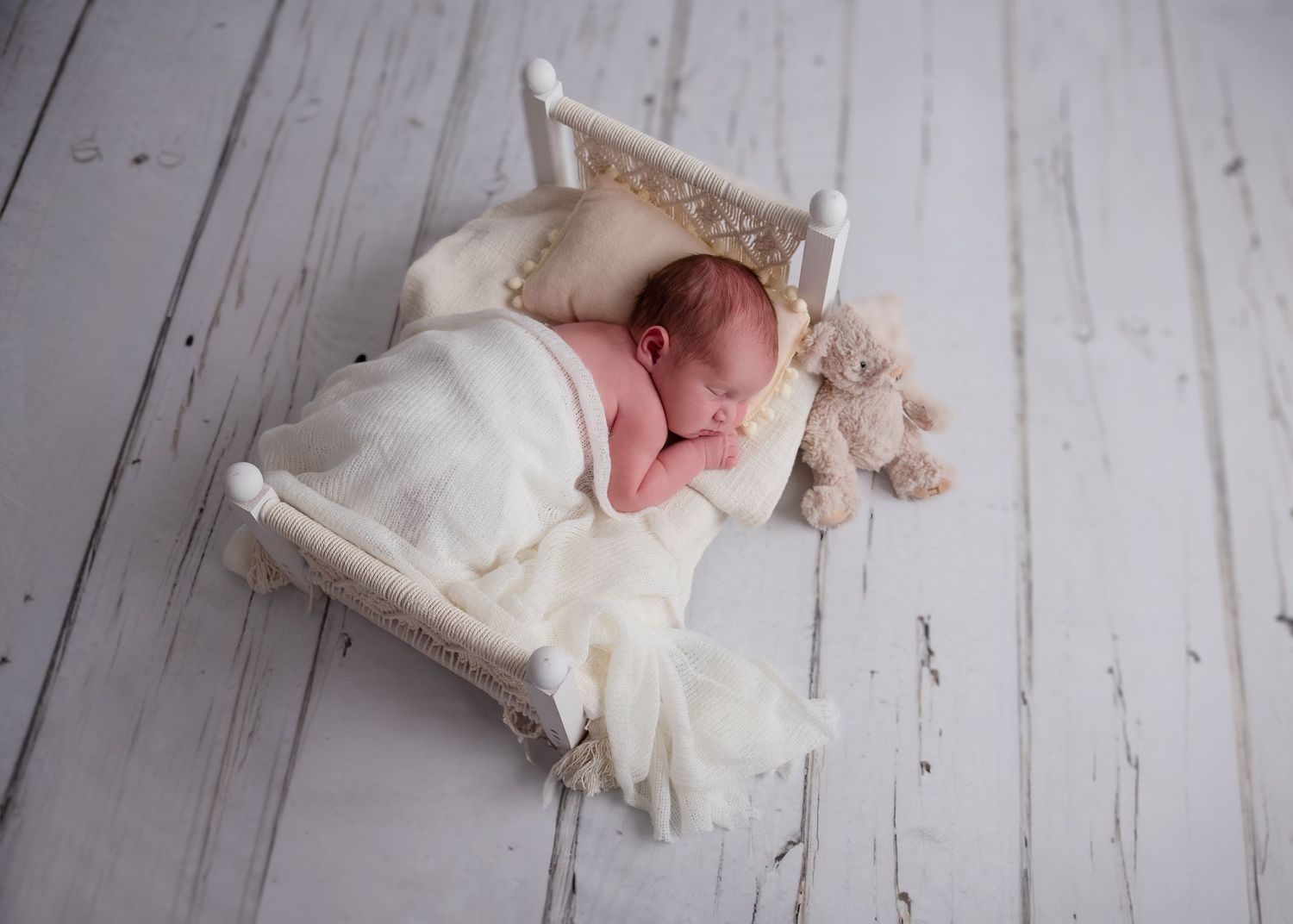 Newborn Photoshoot, of baby laying on a little bed covered with a white blanket taken in Essex Photography Studio