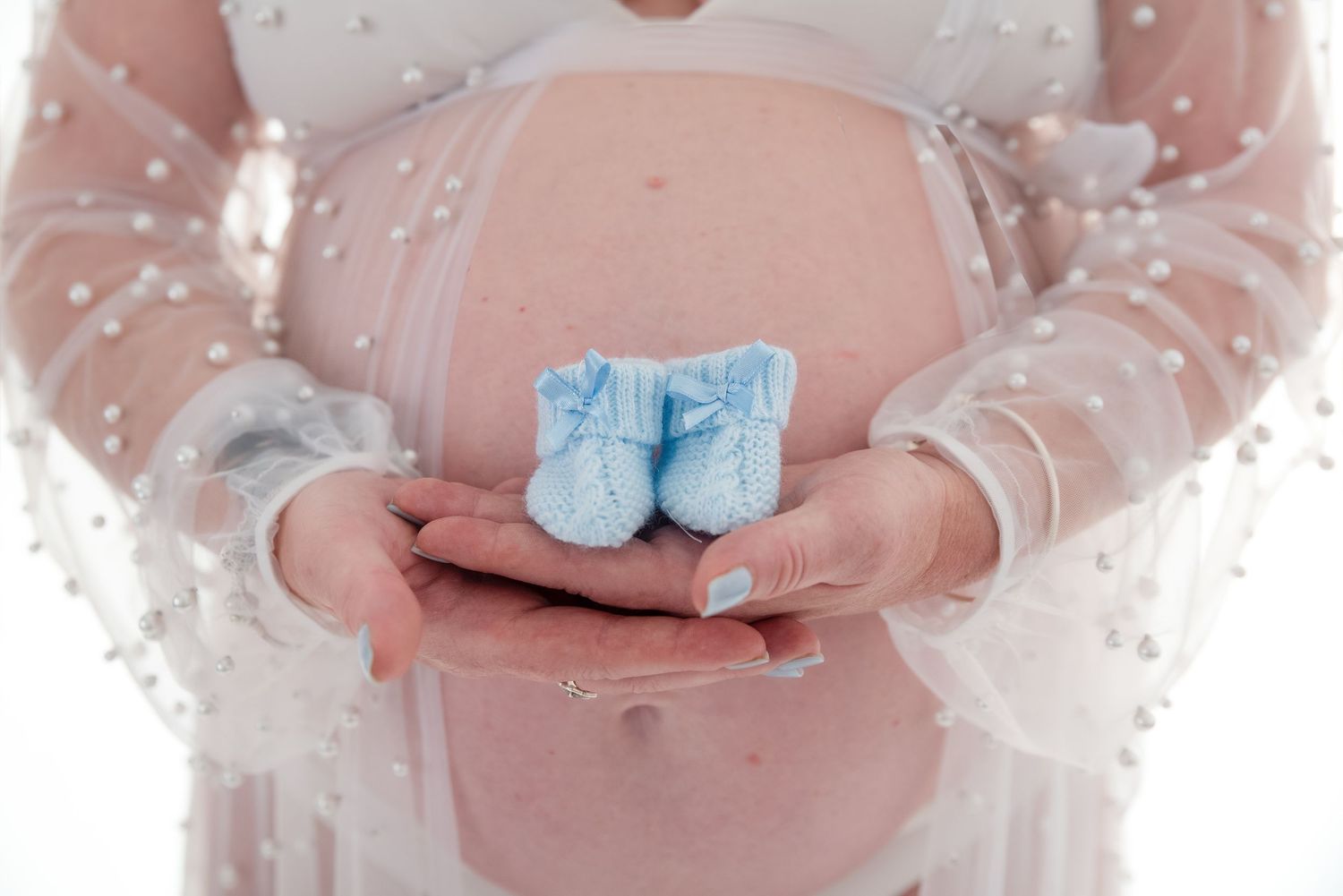 Maternity photo series showing hands cradling baby bump with soft pink lighting effects.