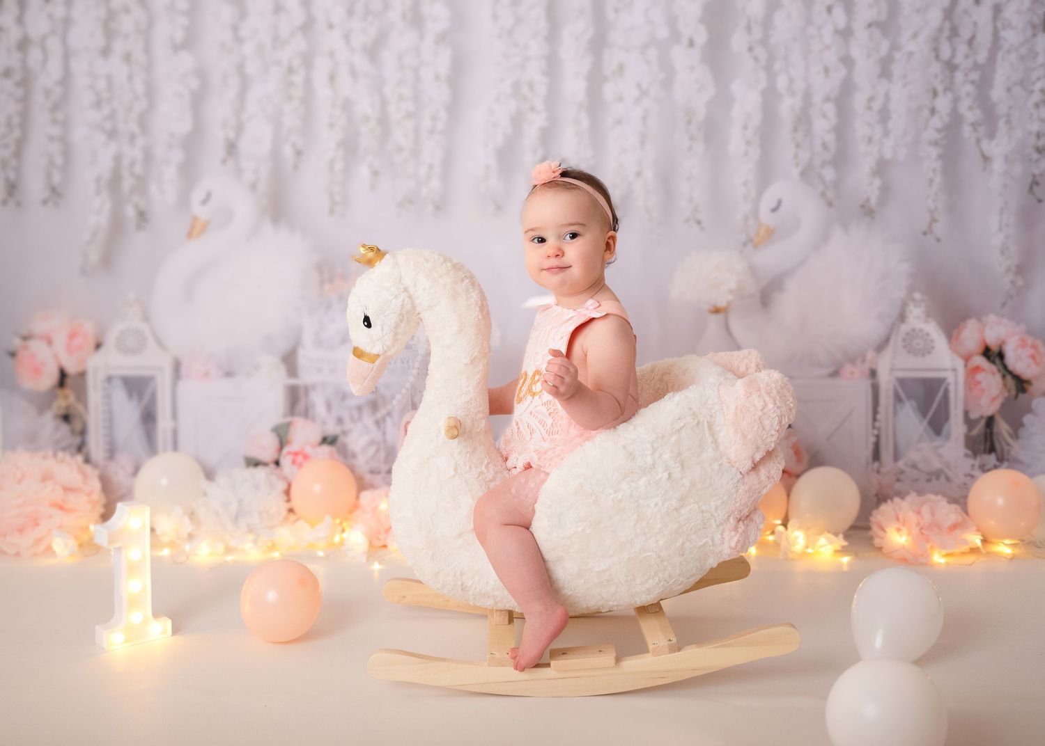 Enchanting baby photo setup with twinkling lights, white swan prop, and dreamy background.