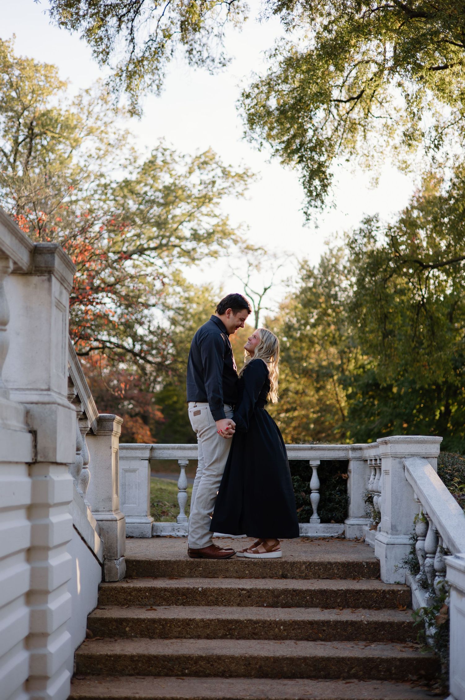 Couple sharing an intimate moment on white stone steps outdoors.