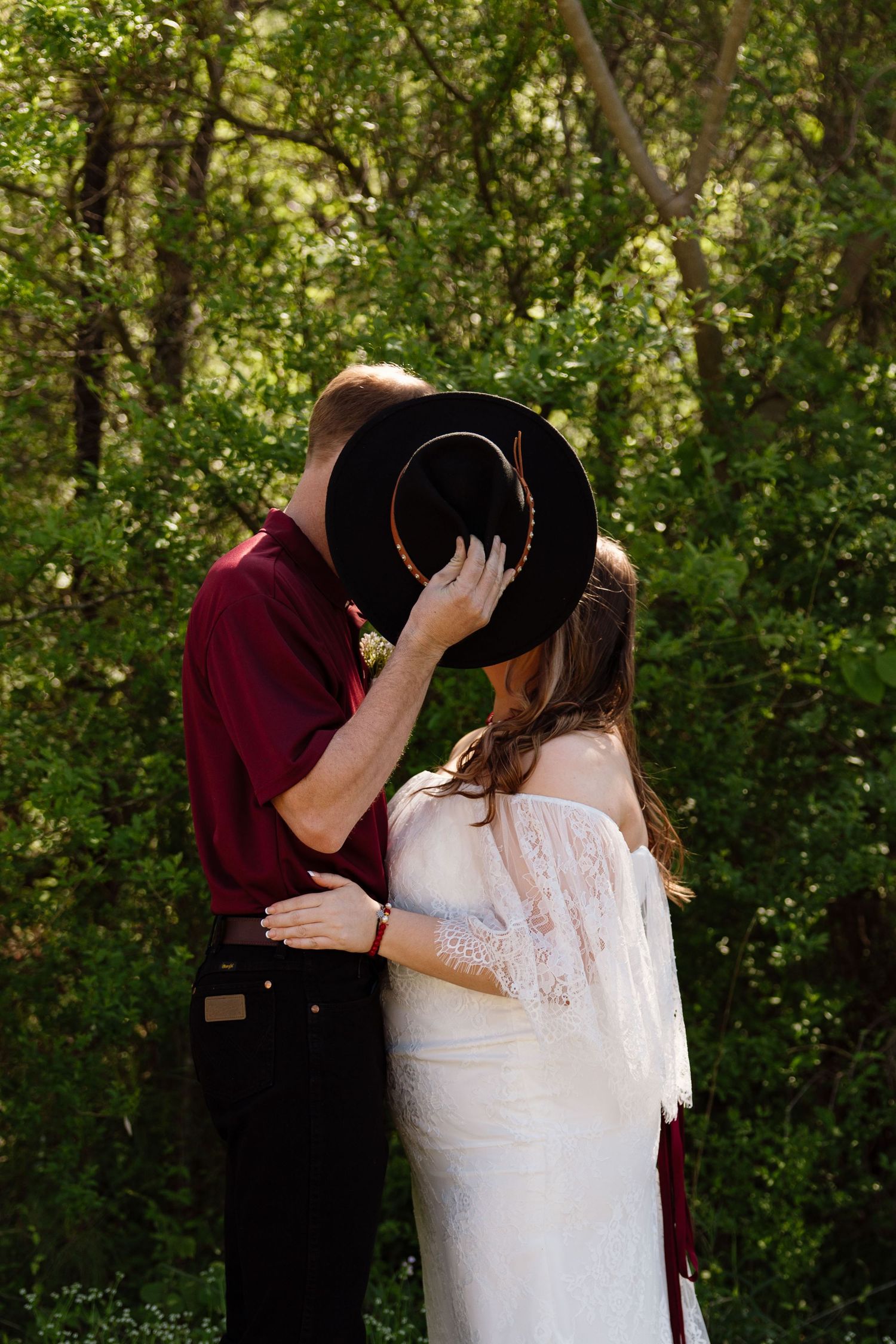 A romantic moment shared between a couple with a black hat hiding their faces.