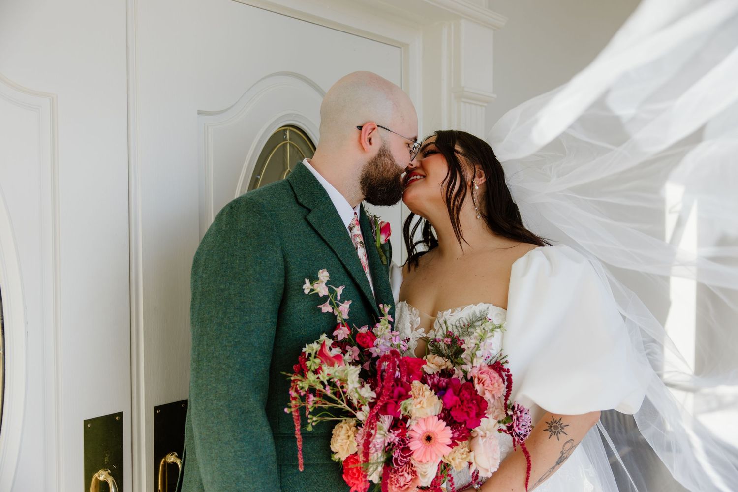 A romantic wedding moment with a flowing veil and colorful bouquet.