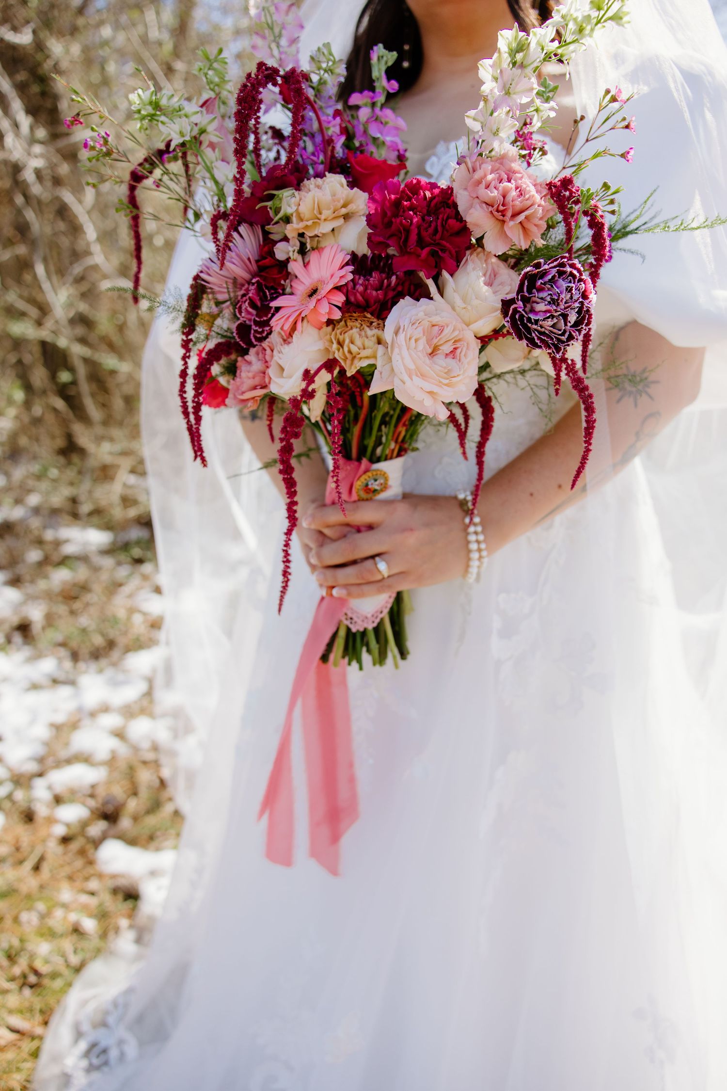 Stunning bridal bouquet with deep burgundy Amaranthus, blush pink roses and white flowers tied with pink ribbons. Wedding Photographer