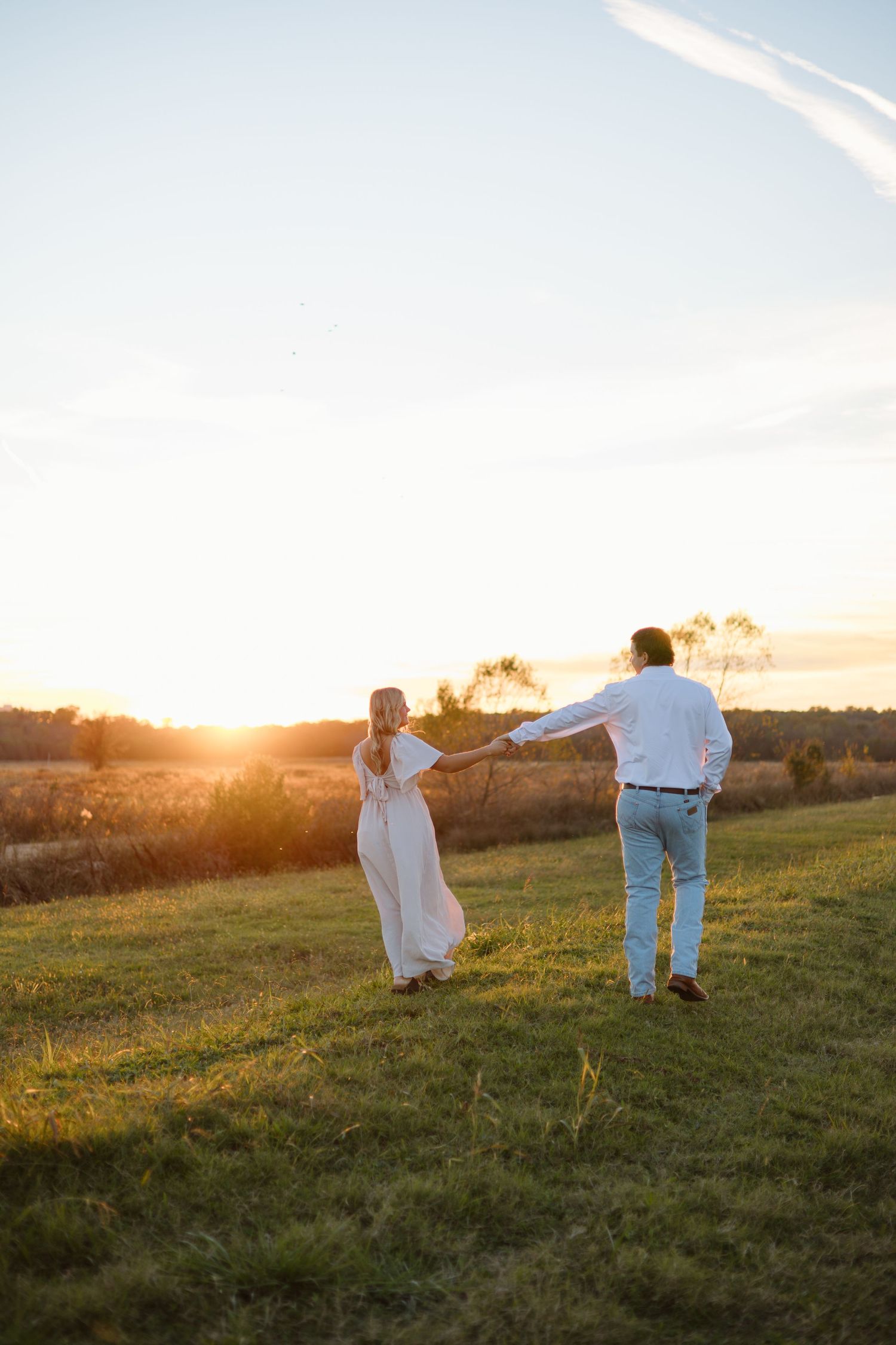 Couple dancing in a golden field during sunset.