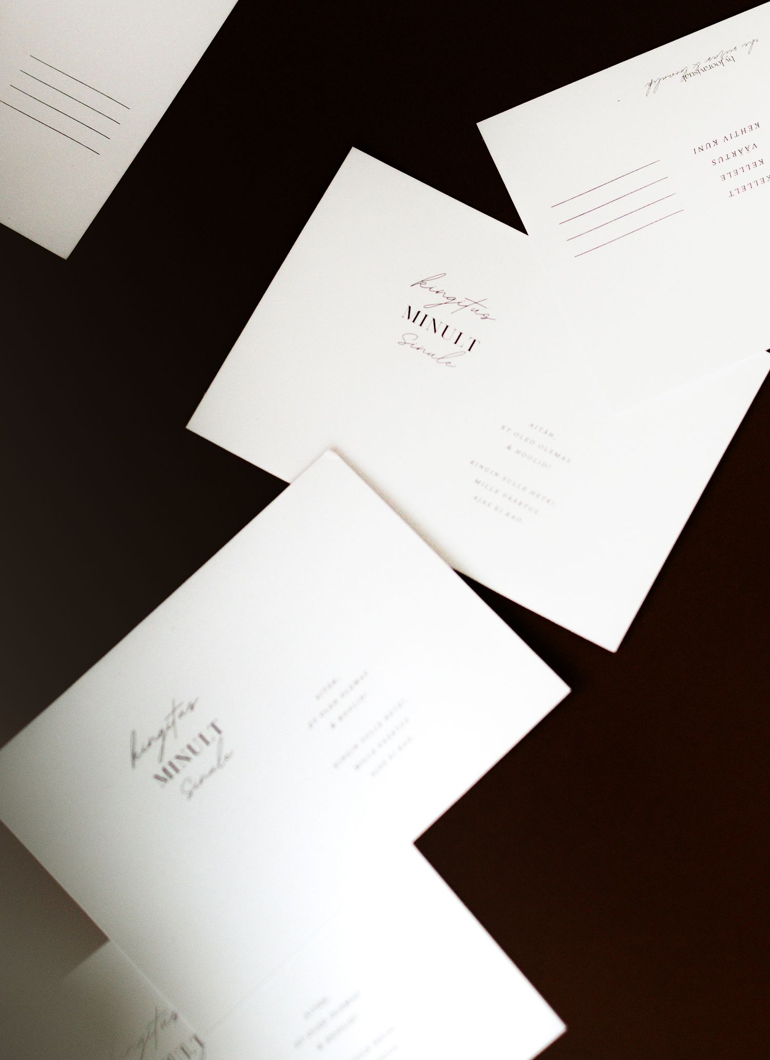 White wedding invitation stationery pieces arranged in an overlapping pattern against a dark background.