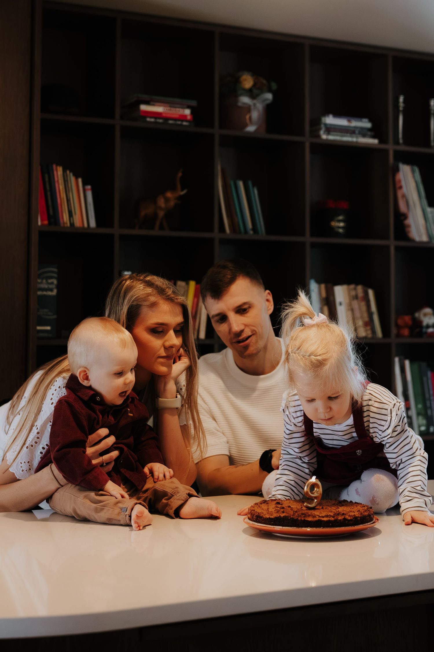 Family gathered around a table with a birthday cake celebrating a special moment together.