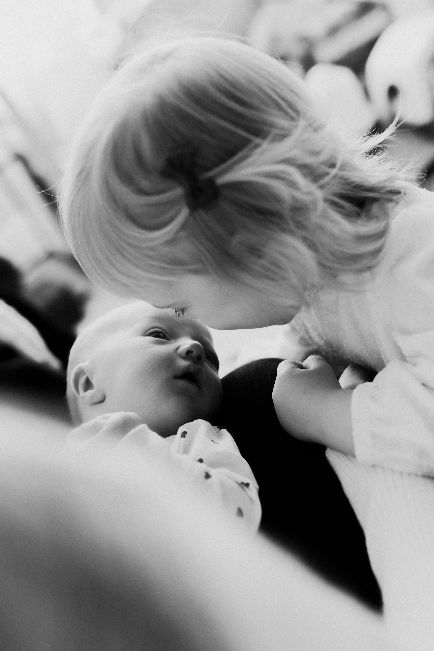 A tender black and white moment between a parent and baby as they share an intimate close-up interaction.