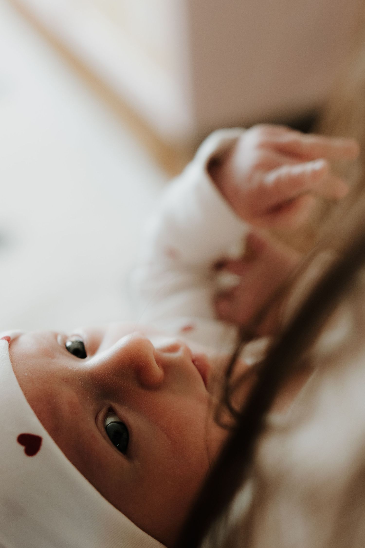 Close-up profile view of a newborn baby resting on white bedding with soft natural lighting.