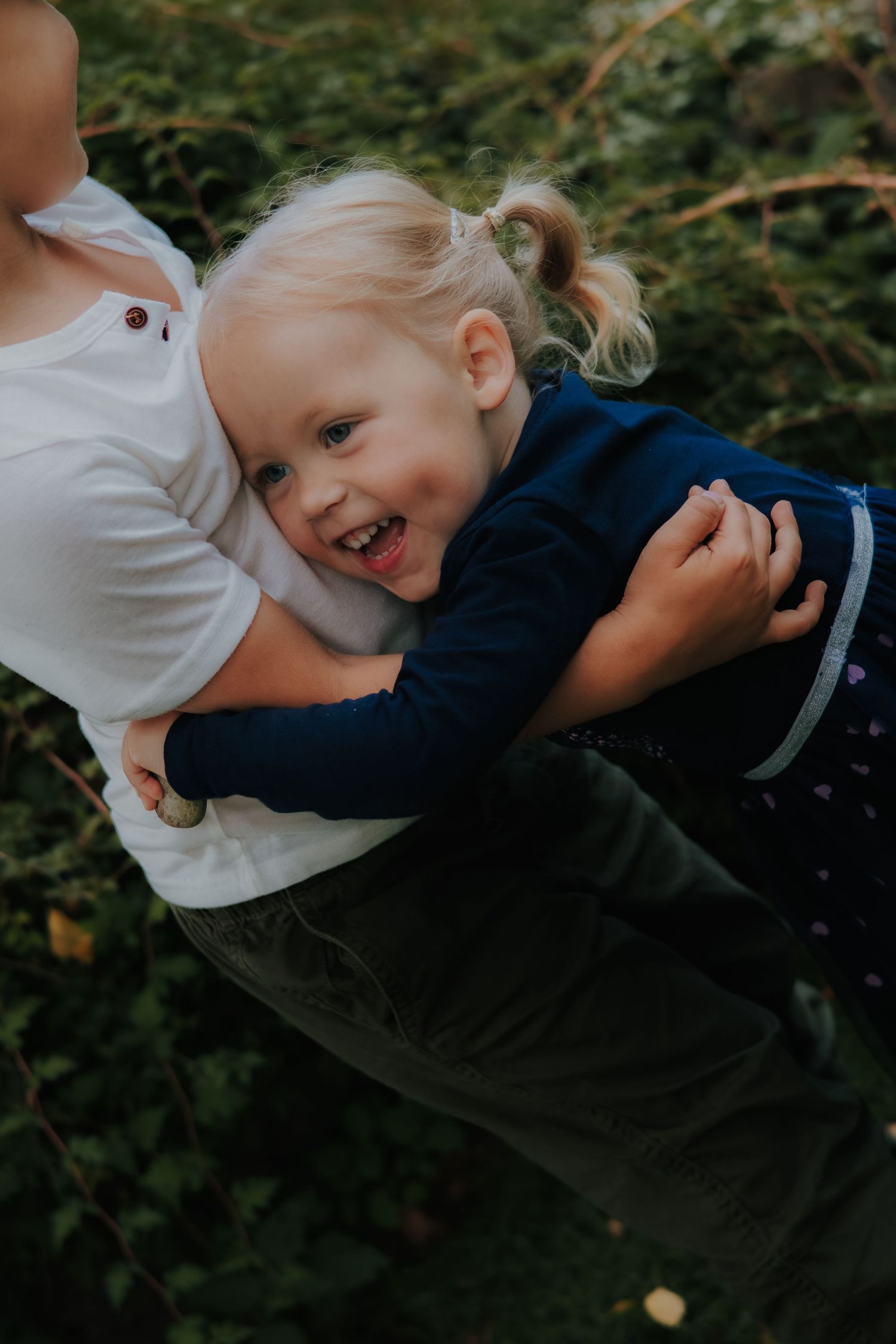 A candid moment of laughter and play captured between parent and child outdoors.