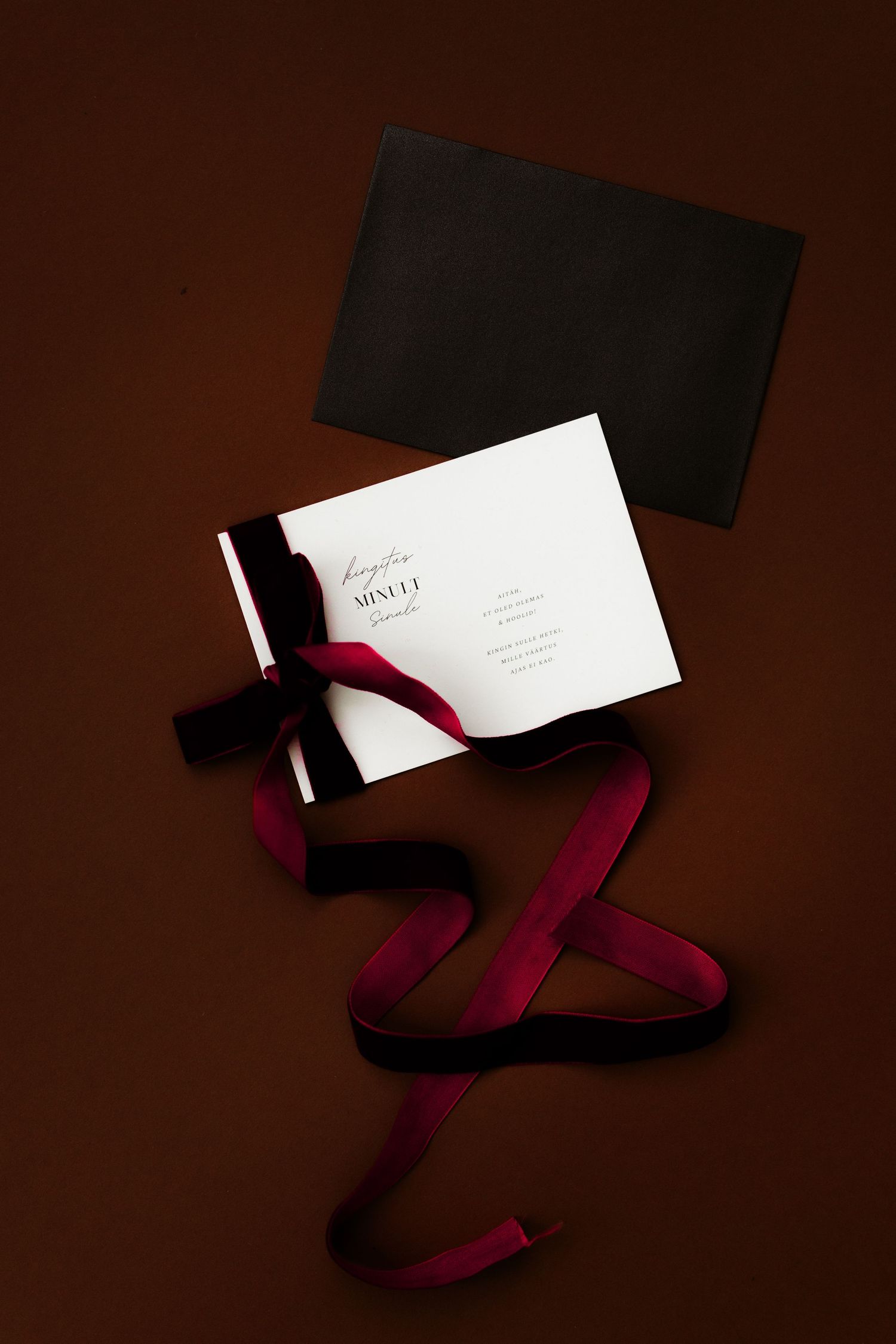 Elegant business cards with burgundy ribbon displayed artistically against dark background.