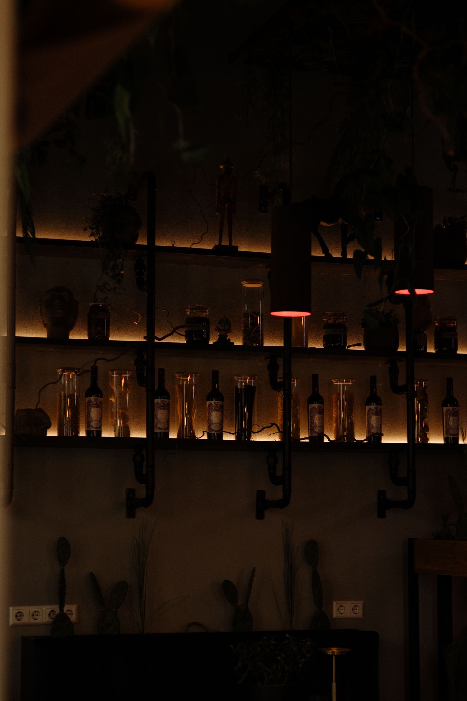 Dimly lit bar interior with illuminated bottles on shelves and warm ambient lighting creating a cozy atmosphere.