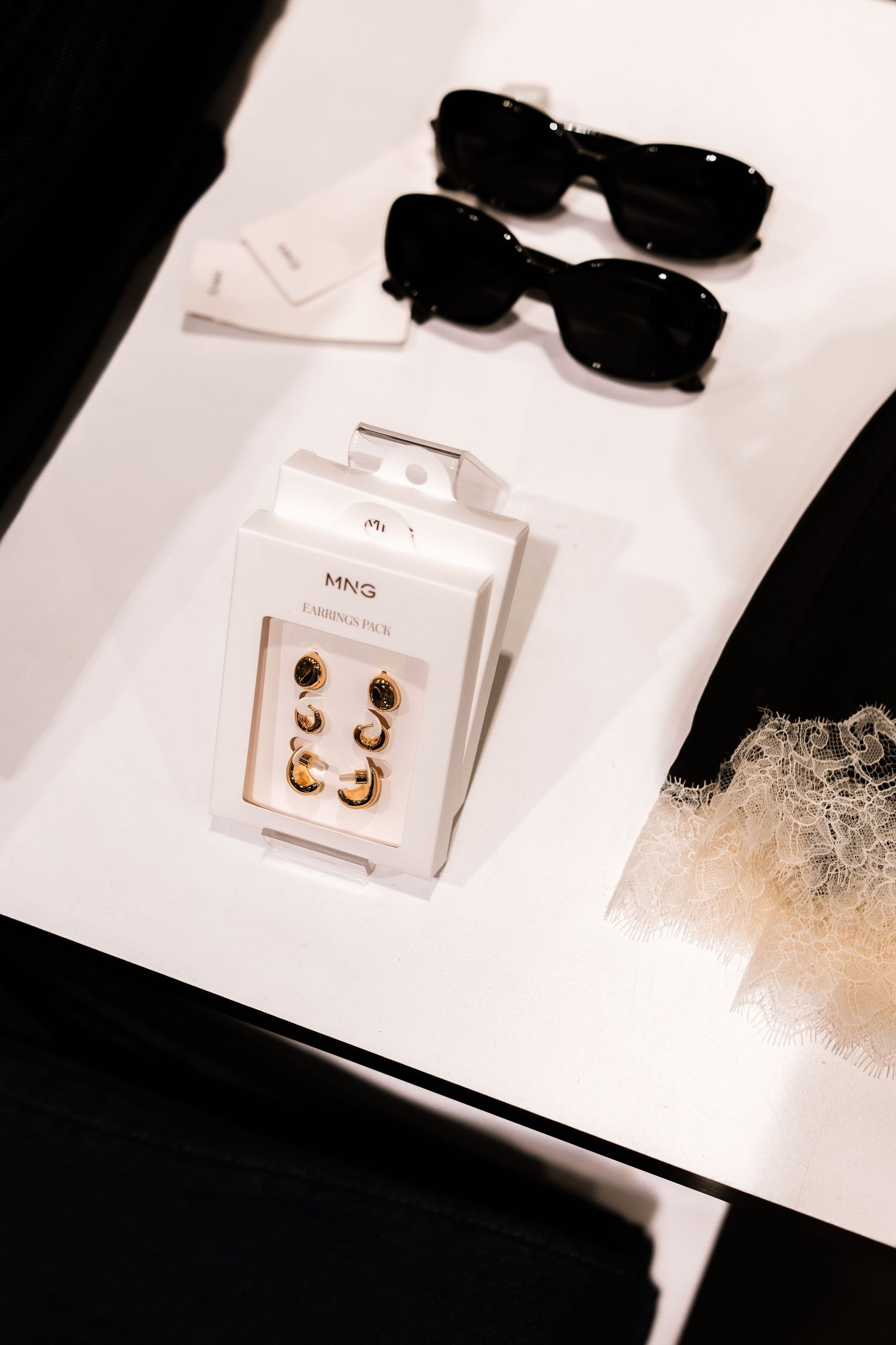Minimalist product photography sequence showing small gold earrings on white cards against dark background.