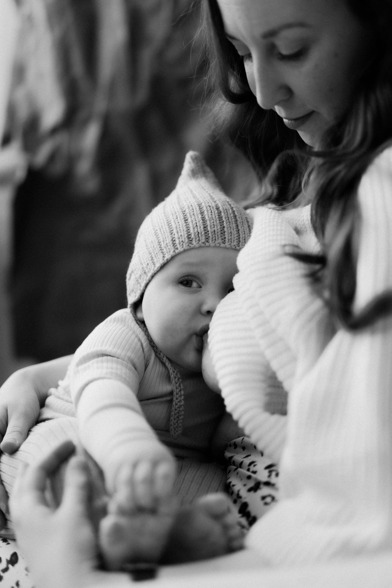 Black and white photo sequence showing tender moments between mother and baby in matching white knit sweaters.